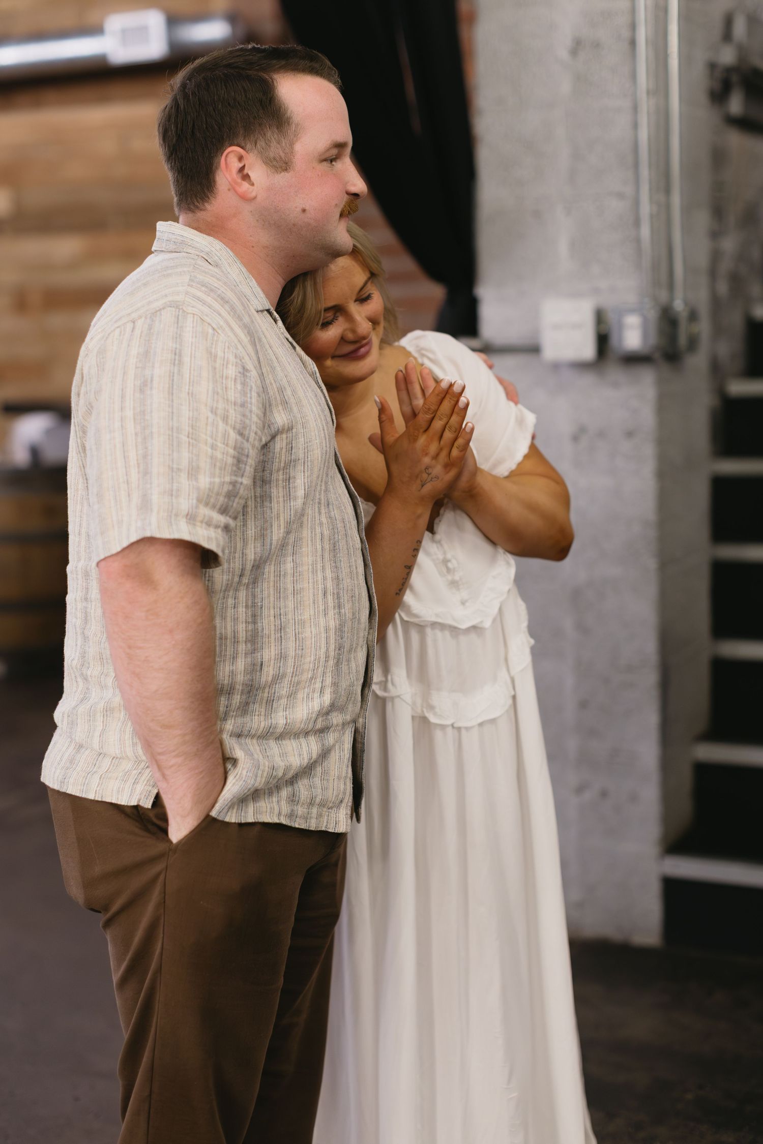 Couple sharing an intimate moment in formal attire at an indoor venue.
