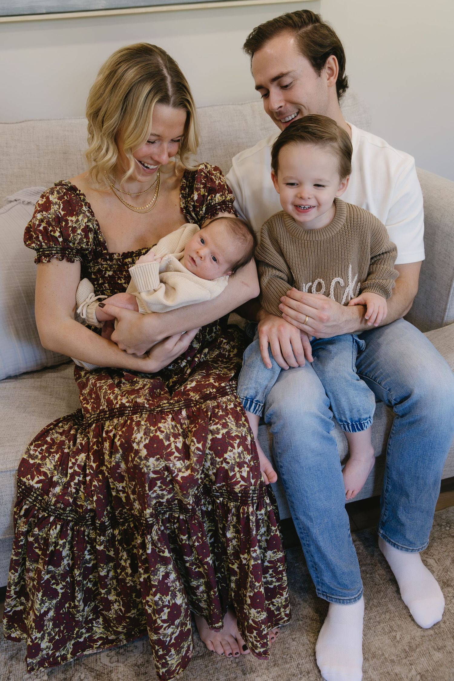 Family sitting together on couch wearing casual clothes in intimate photo series.
