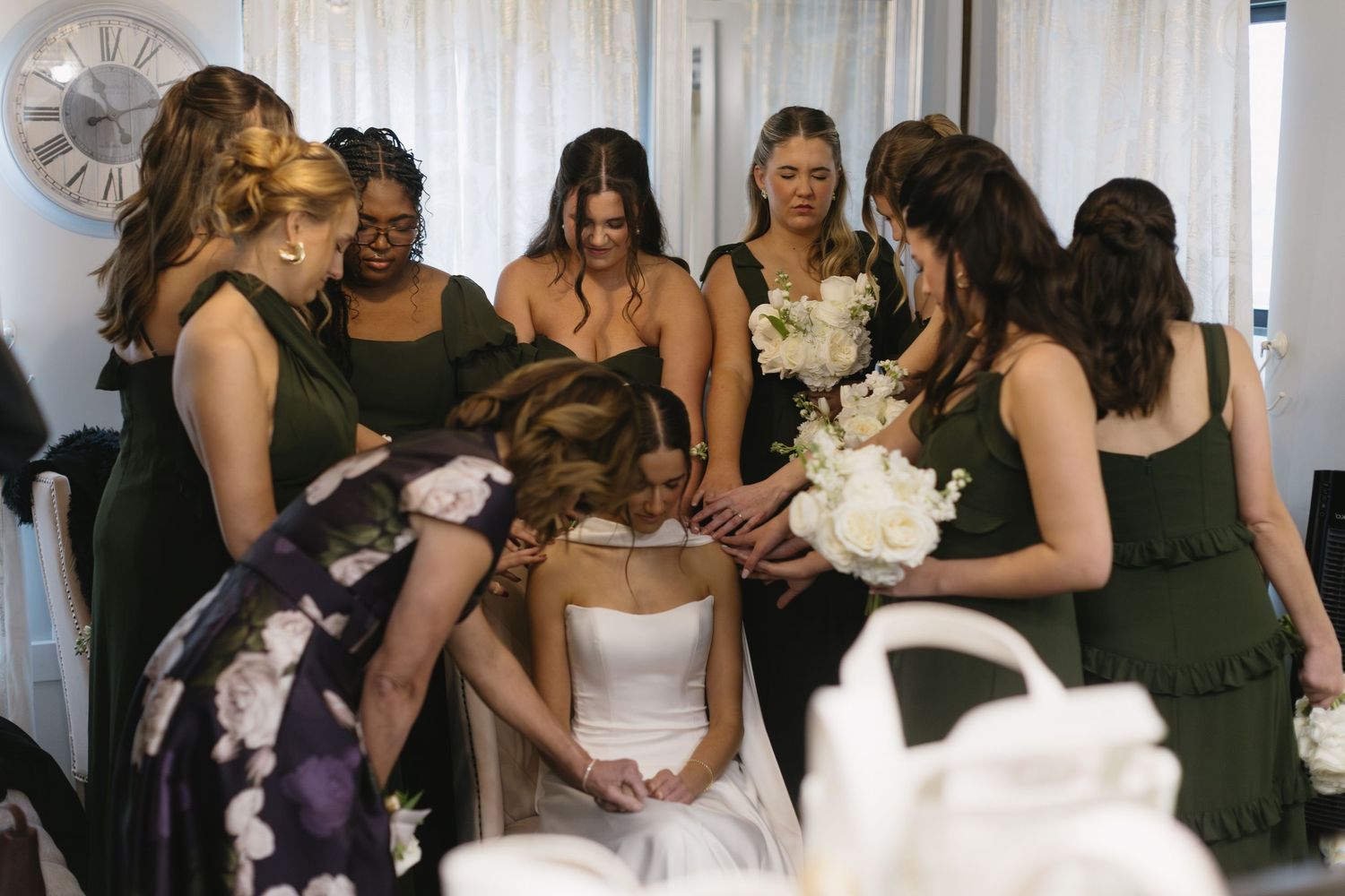 A wedding preparation scene with attendants gathered around in dark dresses.