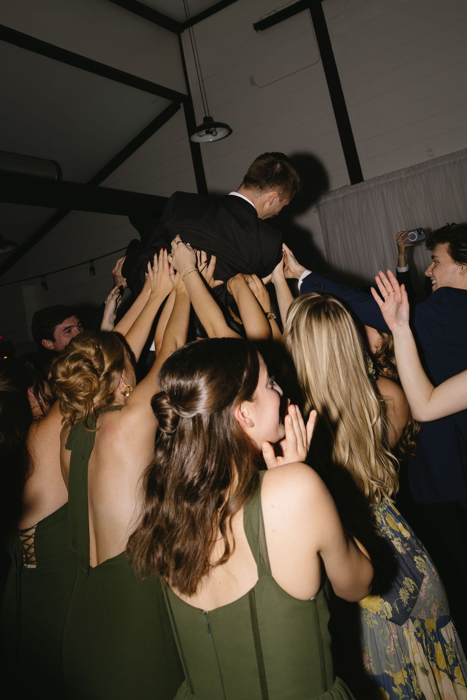 Wedding reception dance floor filled with guests raising hands in celebration.