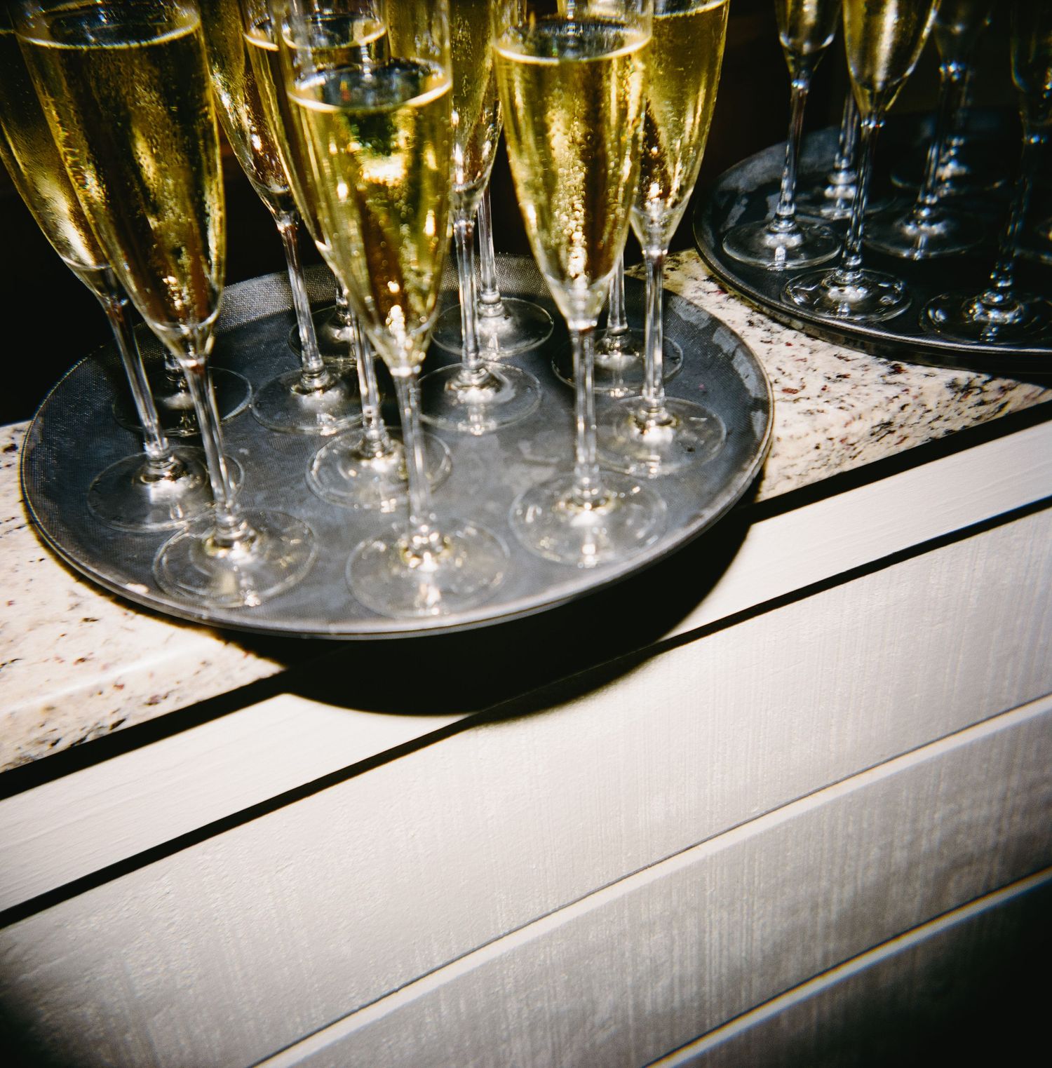 Row of champagne flutes filled with sparkling wine on white surface.