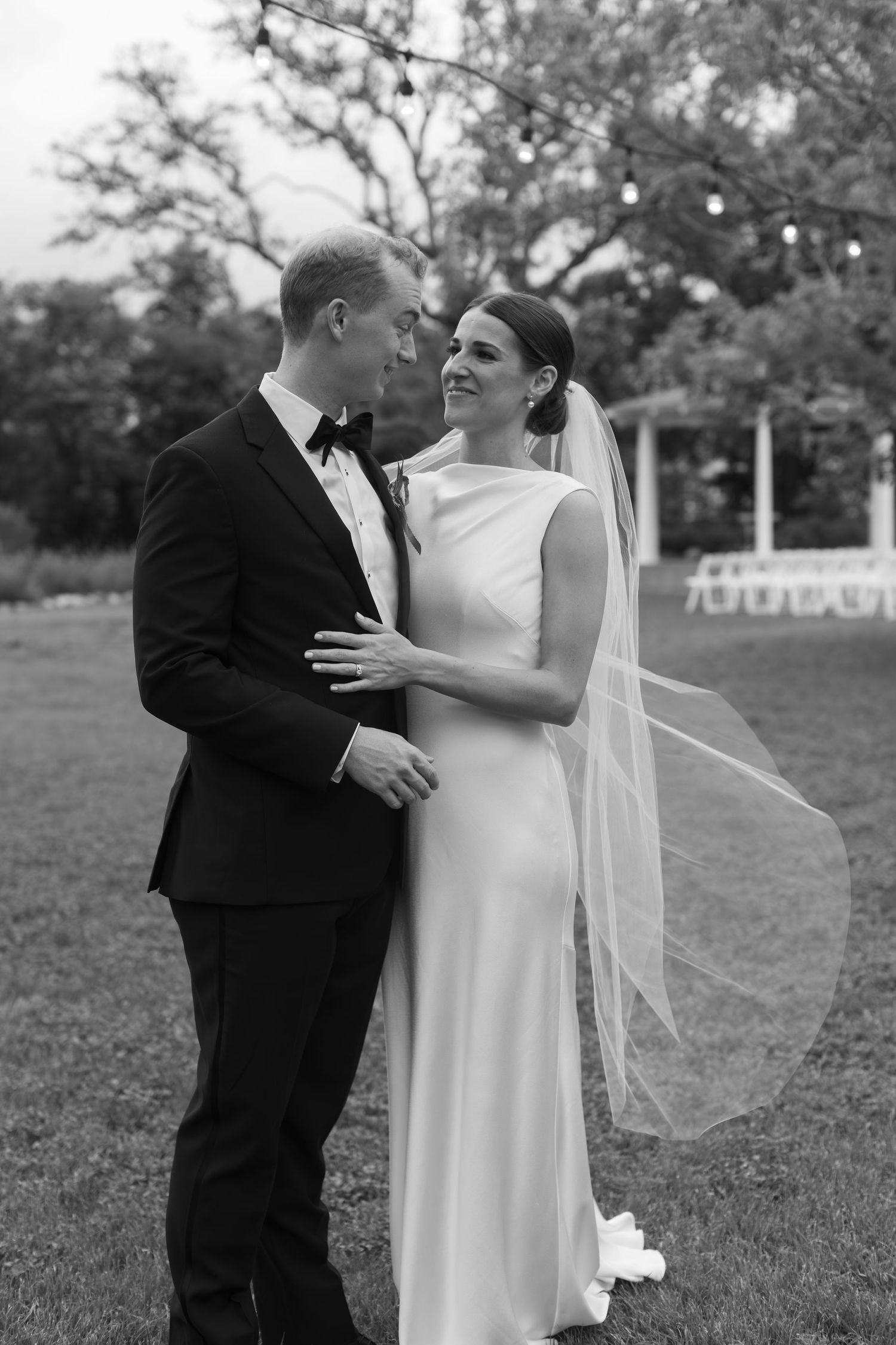 Monochrome romantic sequence of a couple embracing on a grassy lawn during their wedding day.