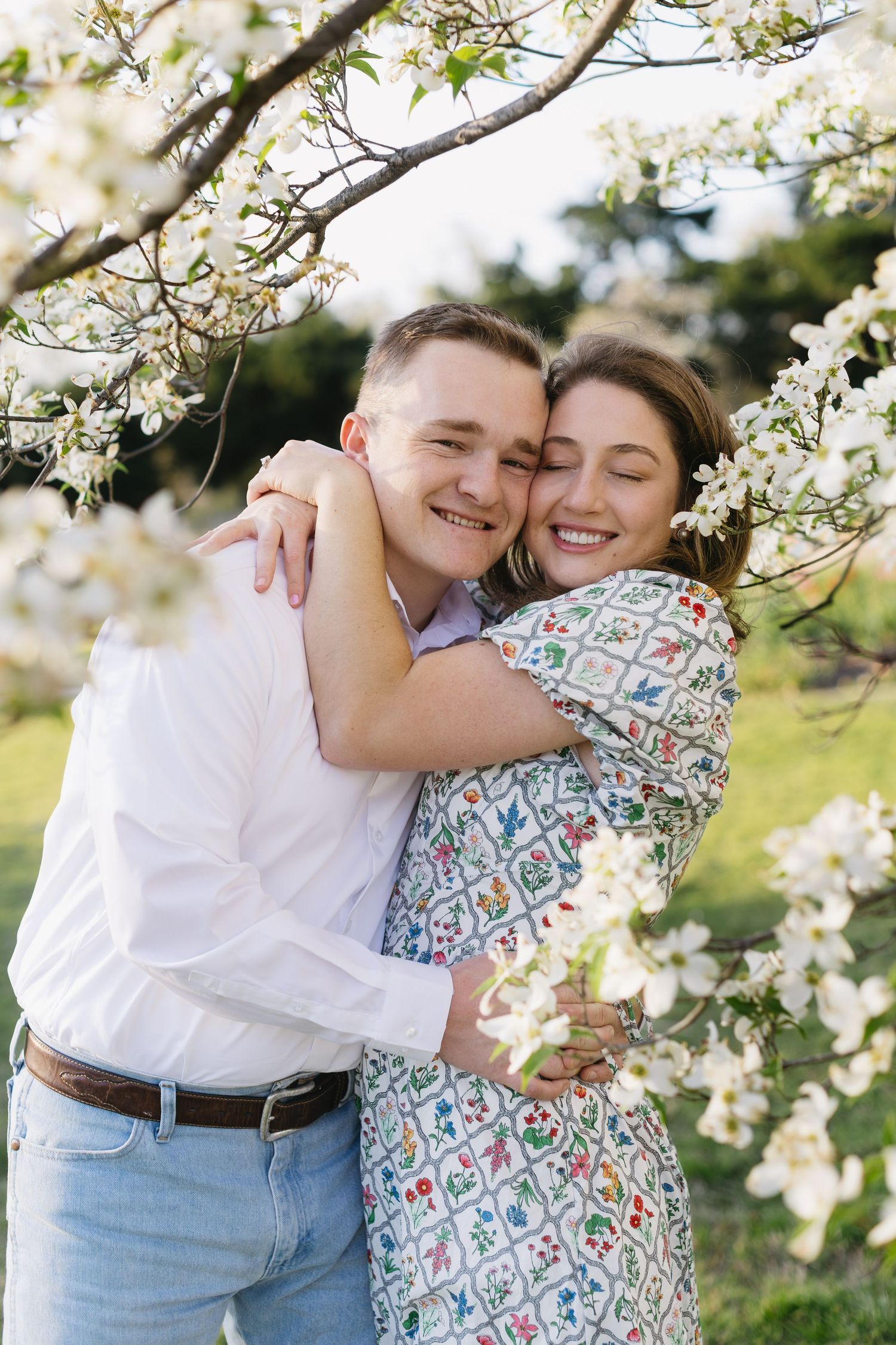 A romantic springtime photoshoot under blooming cherry blossom trees captures intimate embraces.