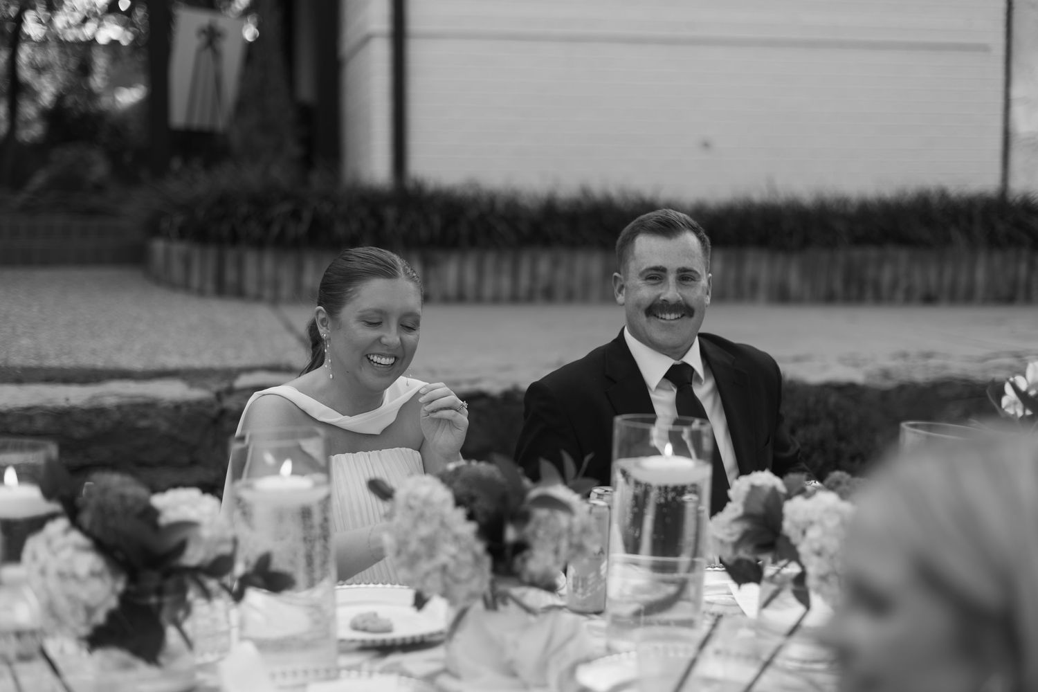 Outdoor wedding reception celebration with tables set under string lights.
