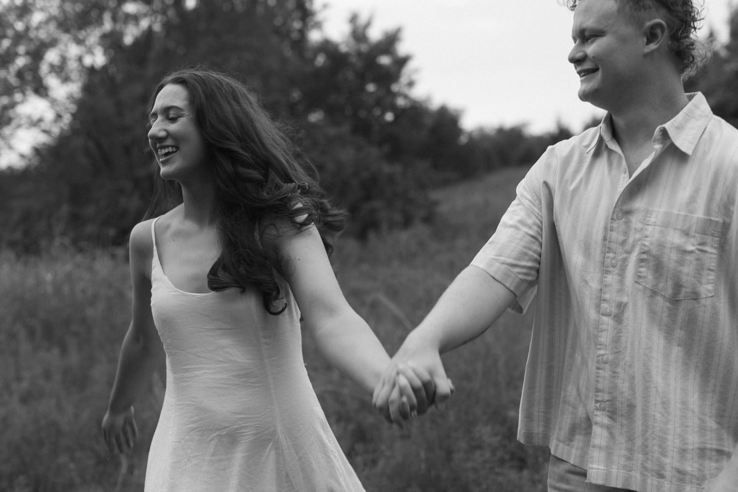 A couple walking together in nature, smiling and enjoying each other's company during a candid photoshoot.