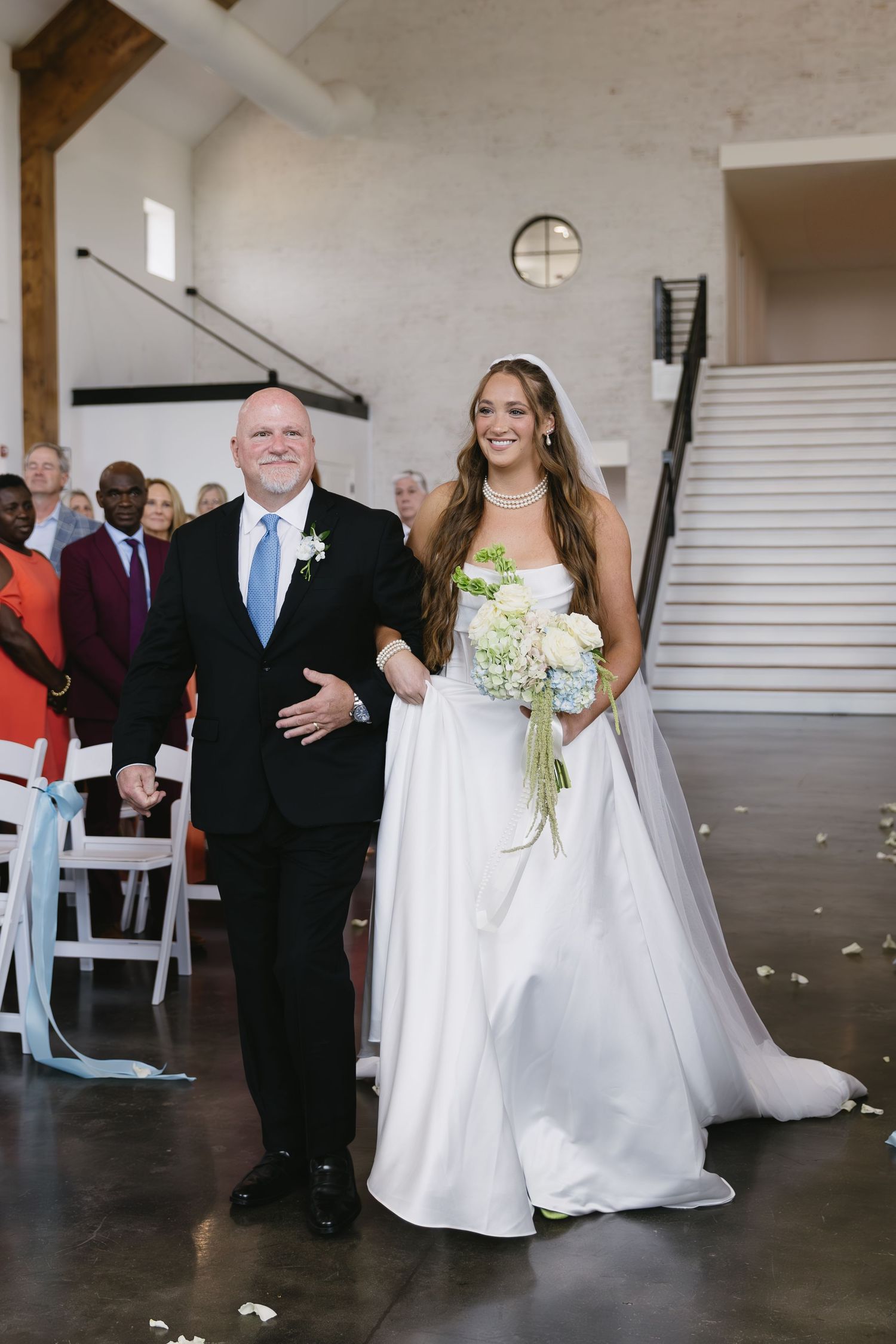 Wedding ceremony photos in a modern indoor venue with white walls and guests in attendance.