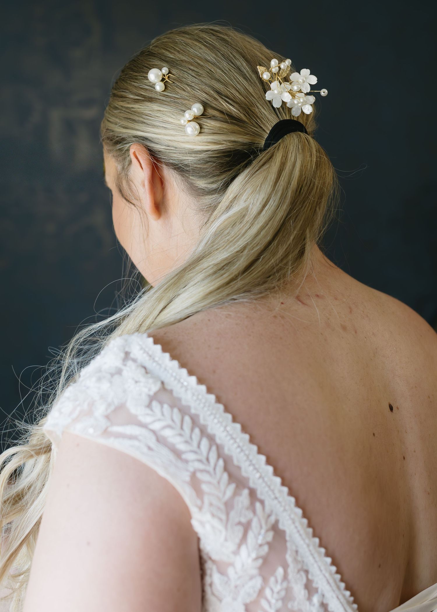 Elegant white lace back detail of a wedding dress with delicate leaf patterns and pearl buttons.