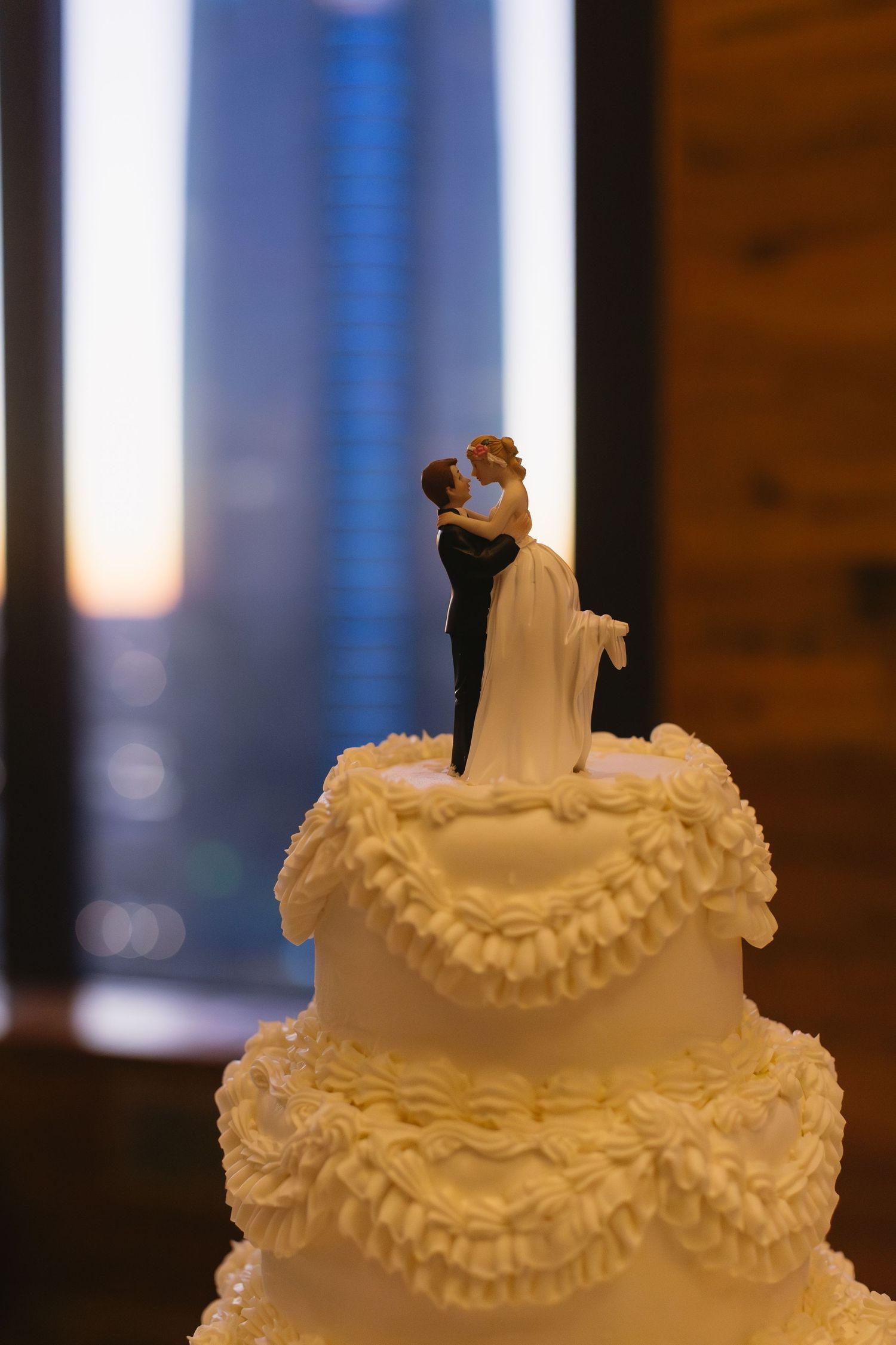 A classic white wedding cake topped with a traditional bride and groom figurine.