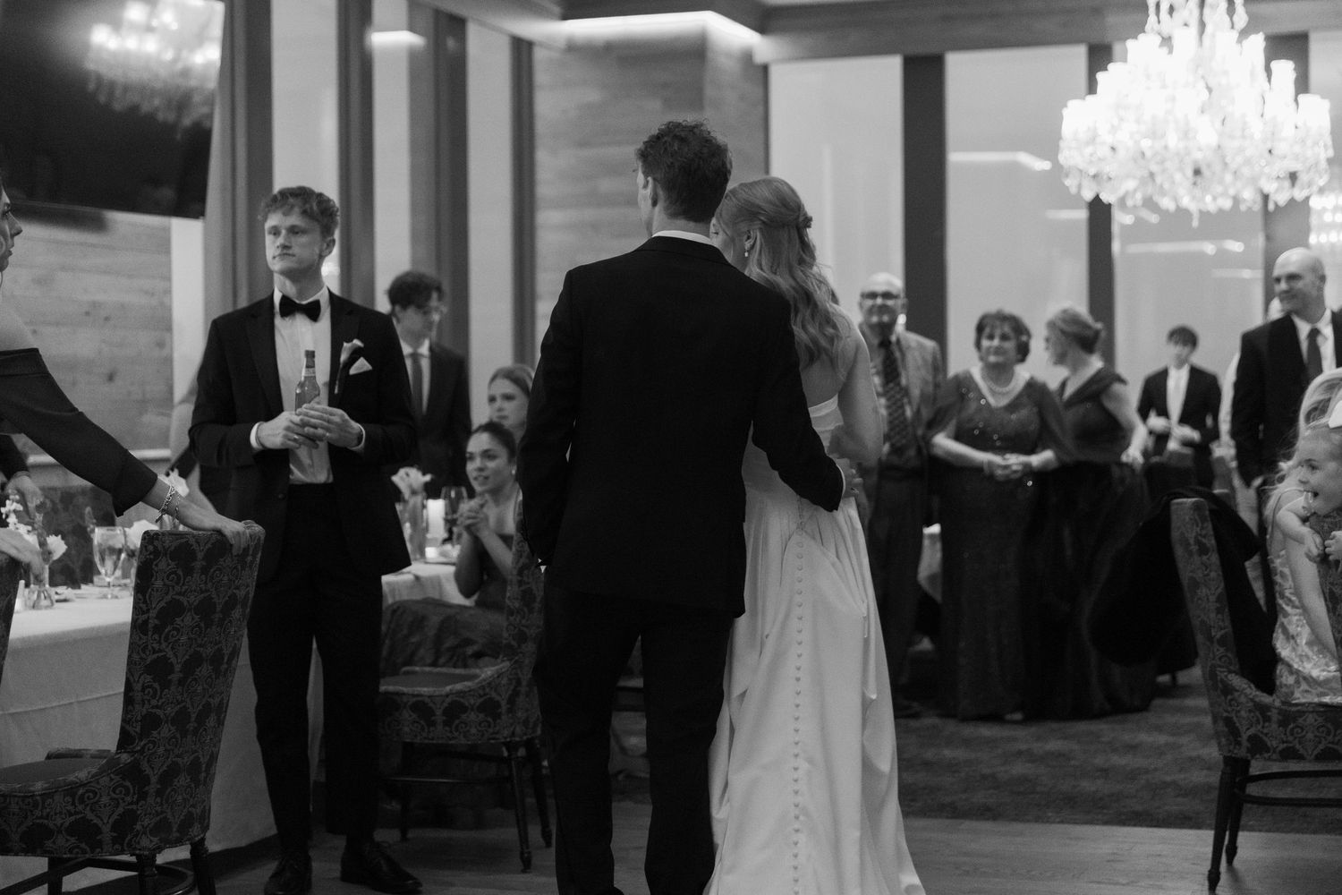 Wedding reception in elegant ballroom with crystal chandeliers and formal gathering.