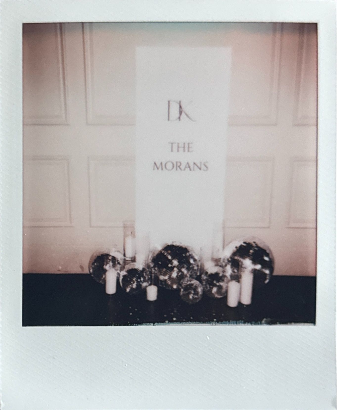 Wedding decor display with 'The Morans' sign and candles arranged at base.
