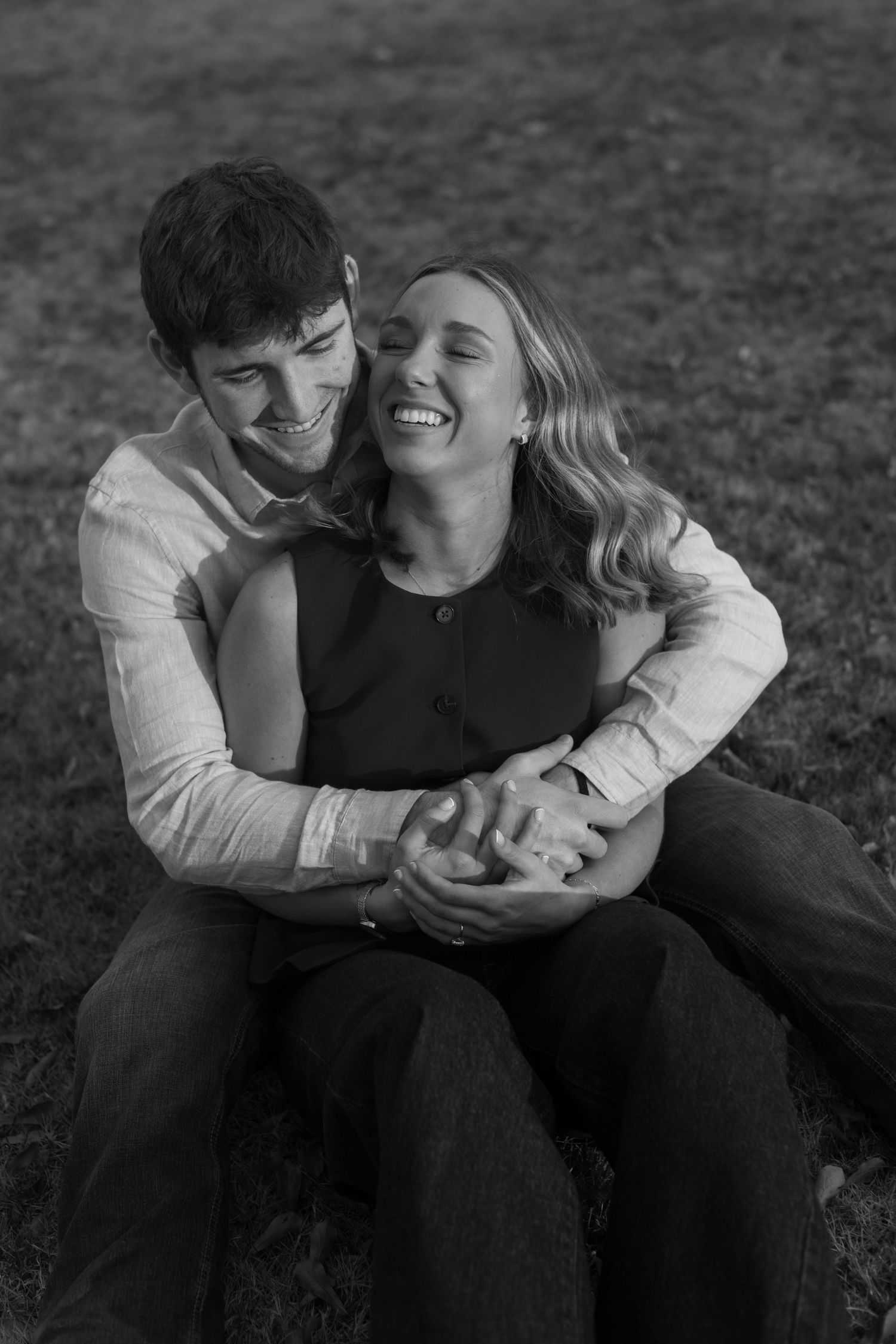 A couple shares intimate black and white moments while sitting together outdoors.