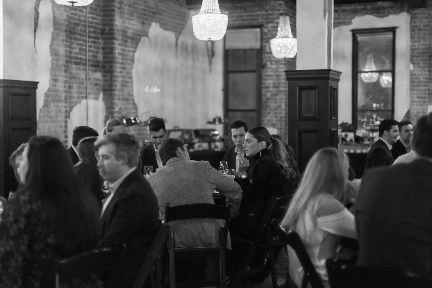 People mingling at an indoor event space with brick walls and ambient lighting.