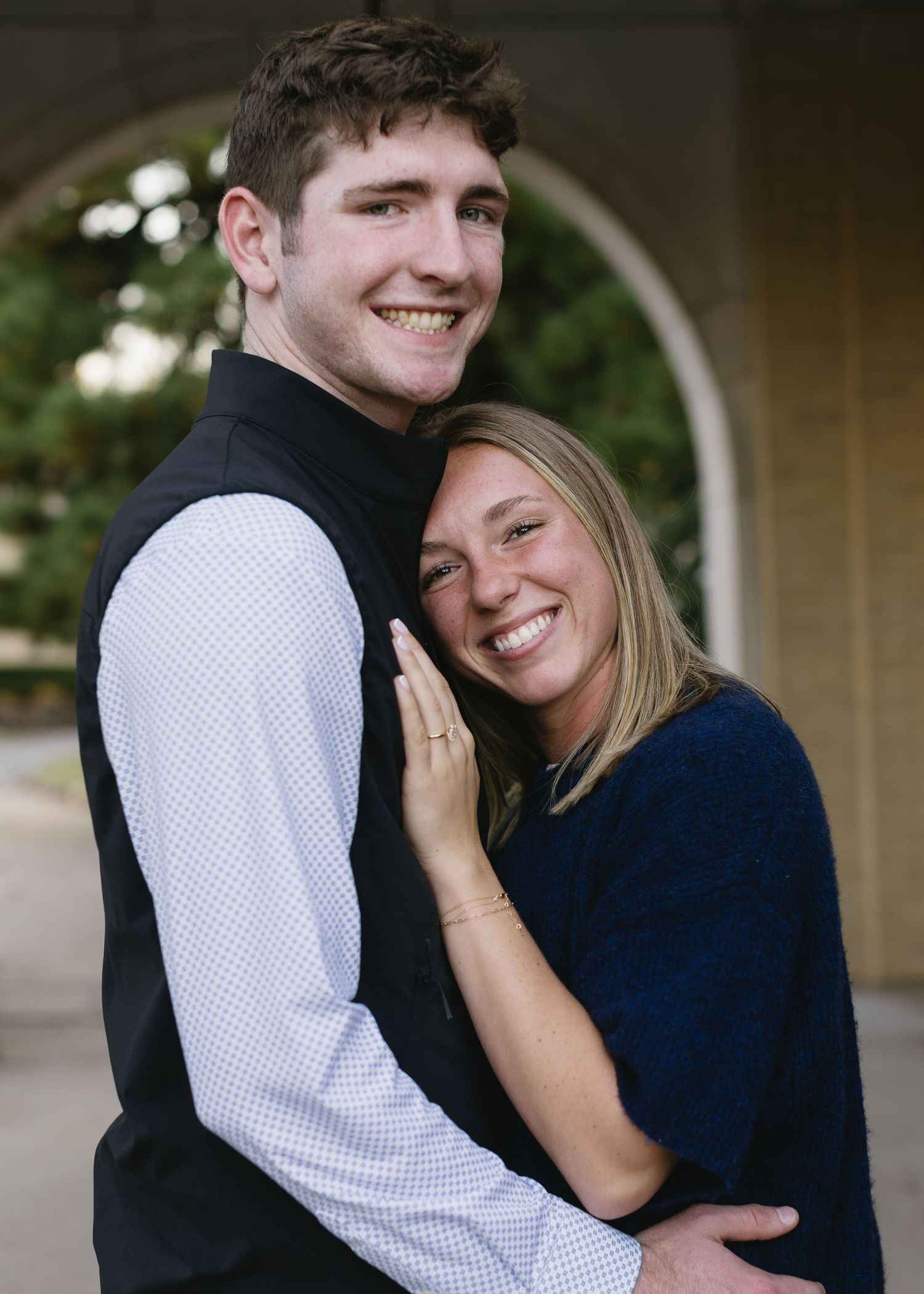 Candid moments captured of a couple laughing and embracing under an architectural archway.