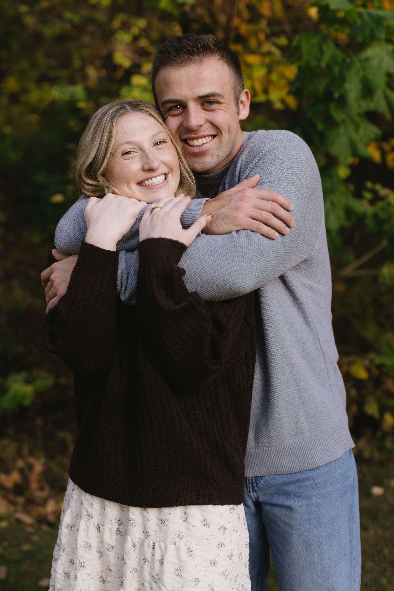 A sweet candid moment captured between a couple laughing and hugging outdoors.