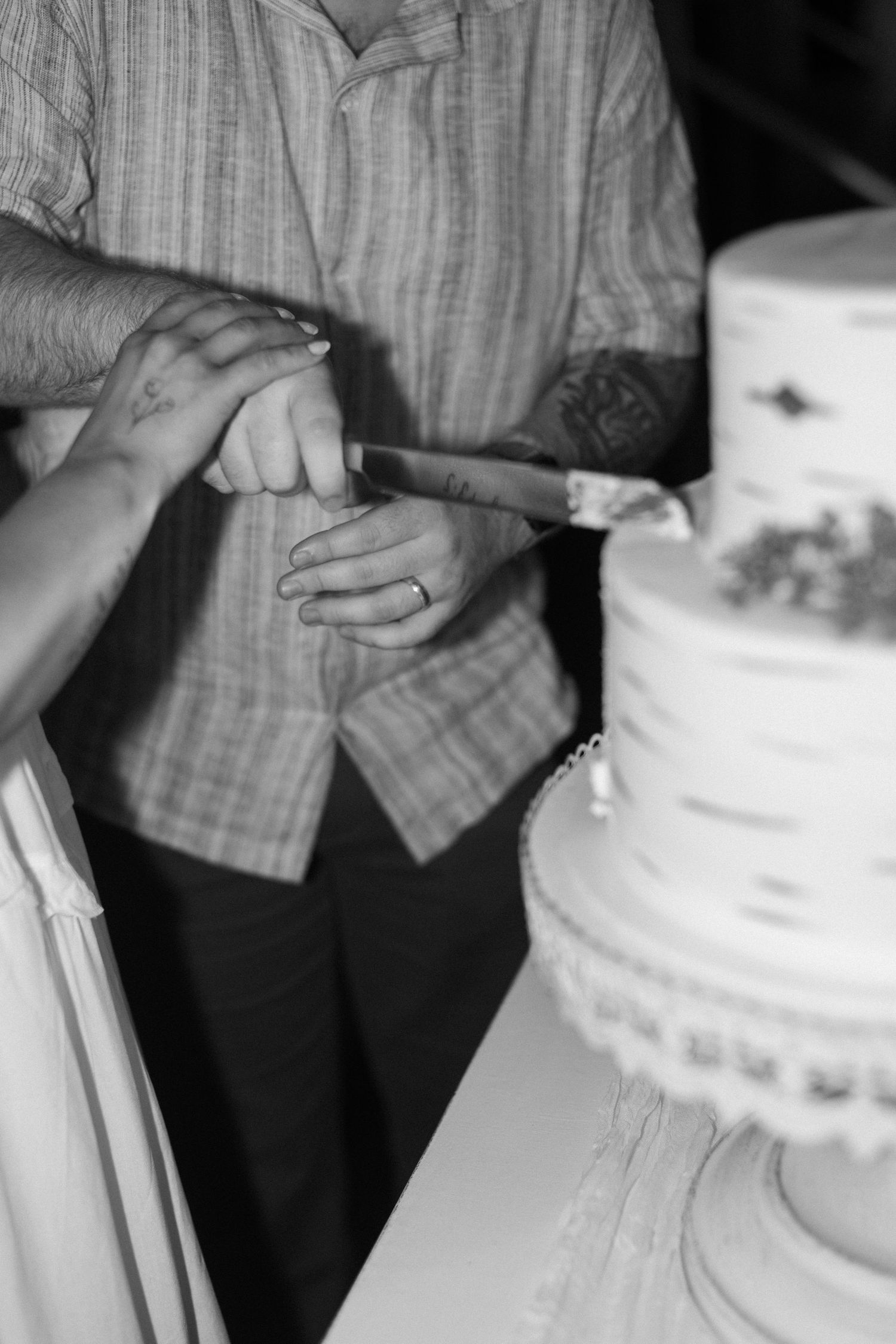 Close-up shot of hands near a white wedding cake.