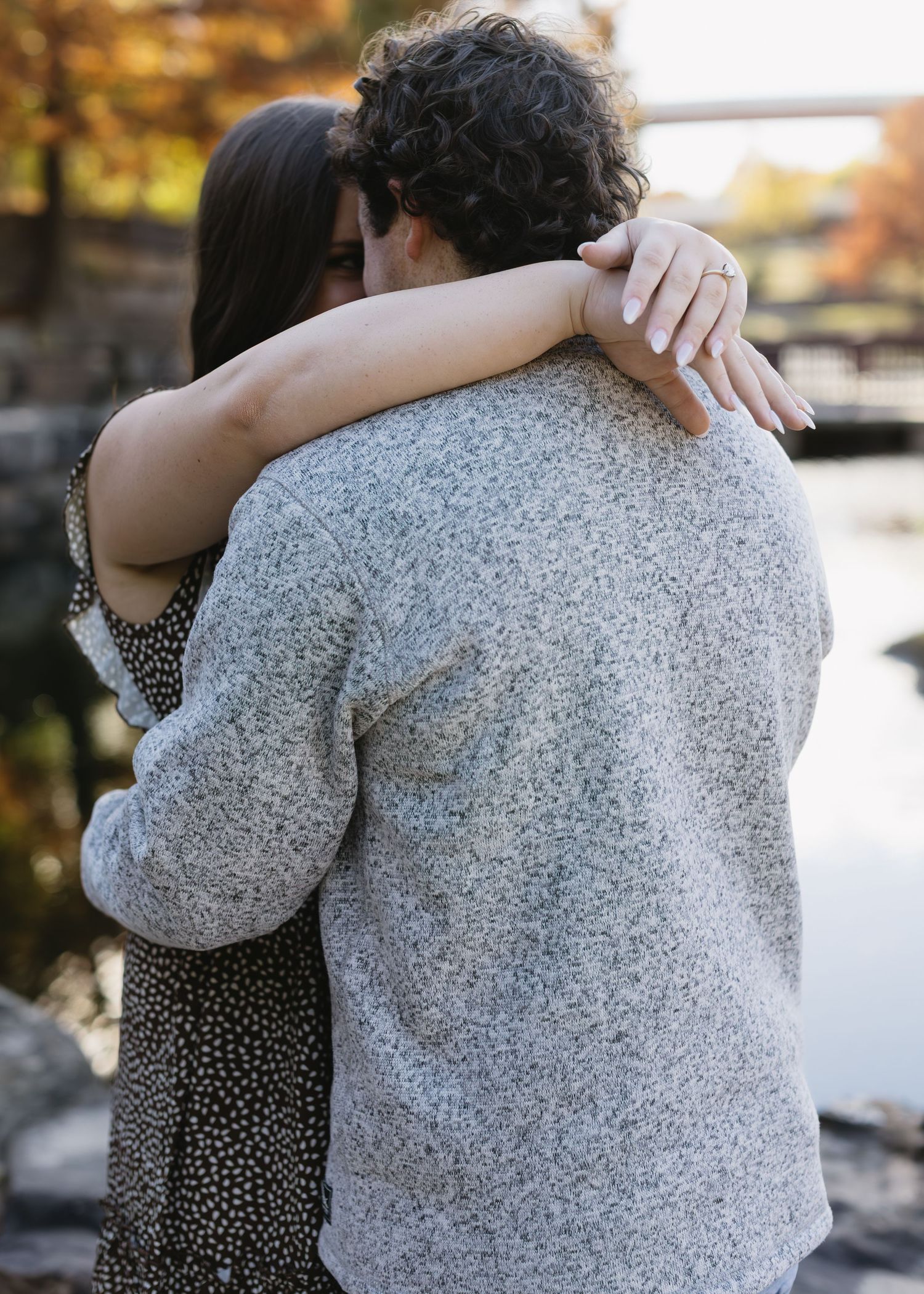A couple shares tender moments together during an outdoor autumn photoshoot by a lake.