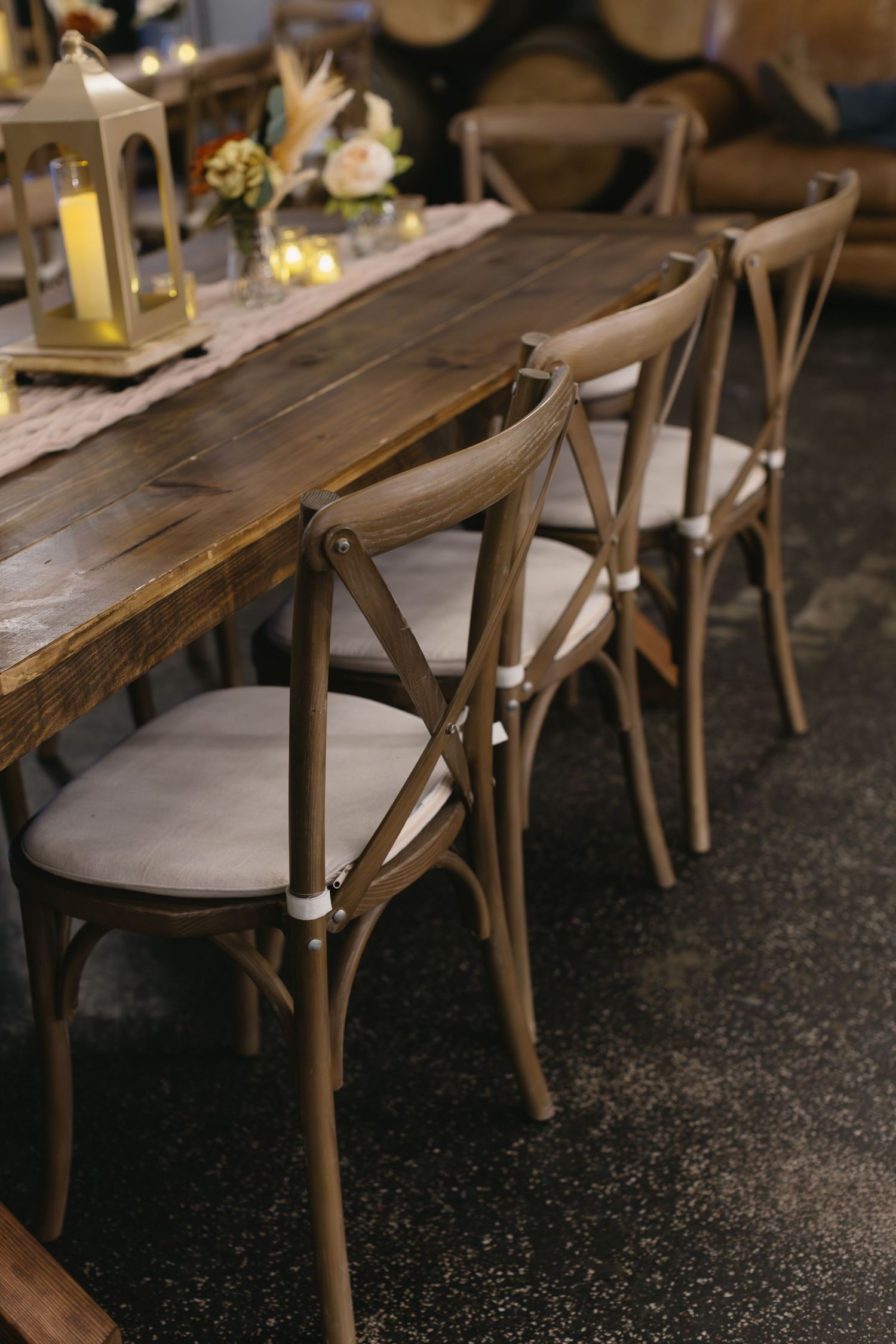 Rustic wooden cross-back chairs lined up along a dark wooden dining table.