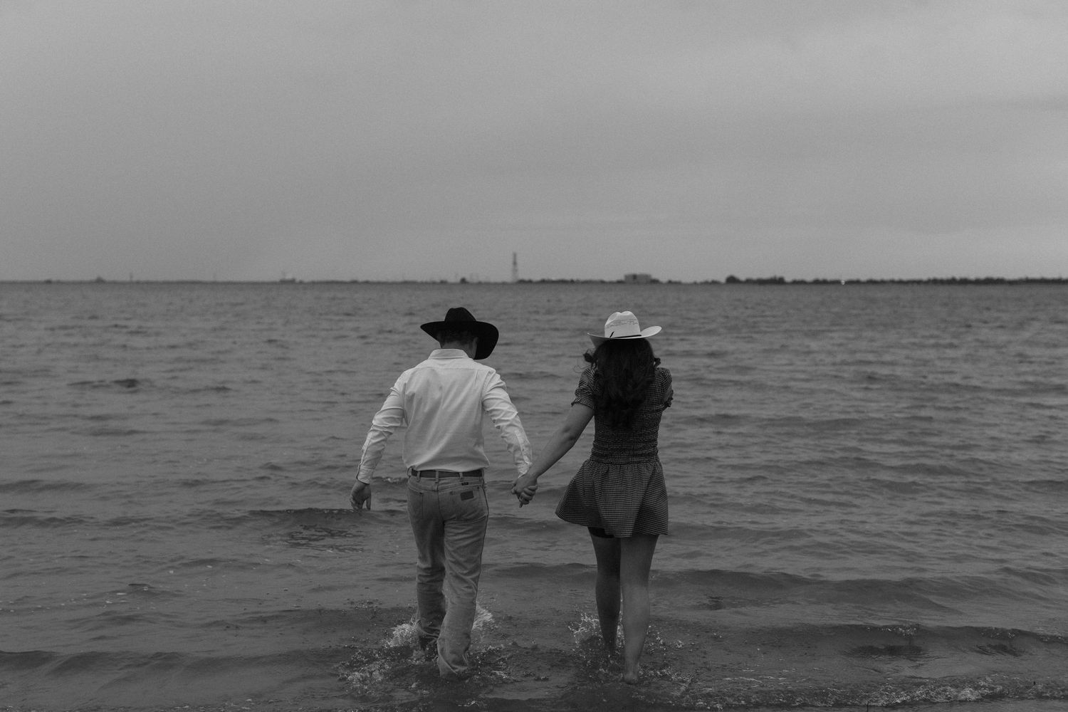 Silhouette of two people walking together along a scenic beach at sunset.