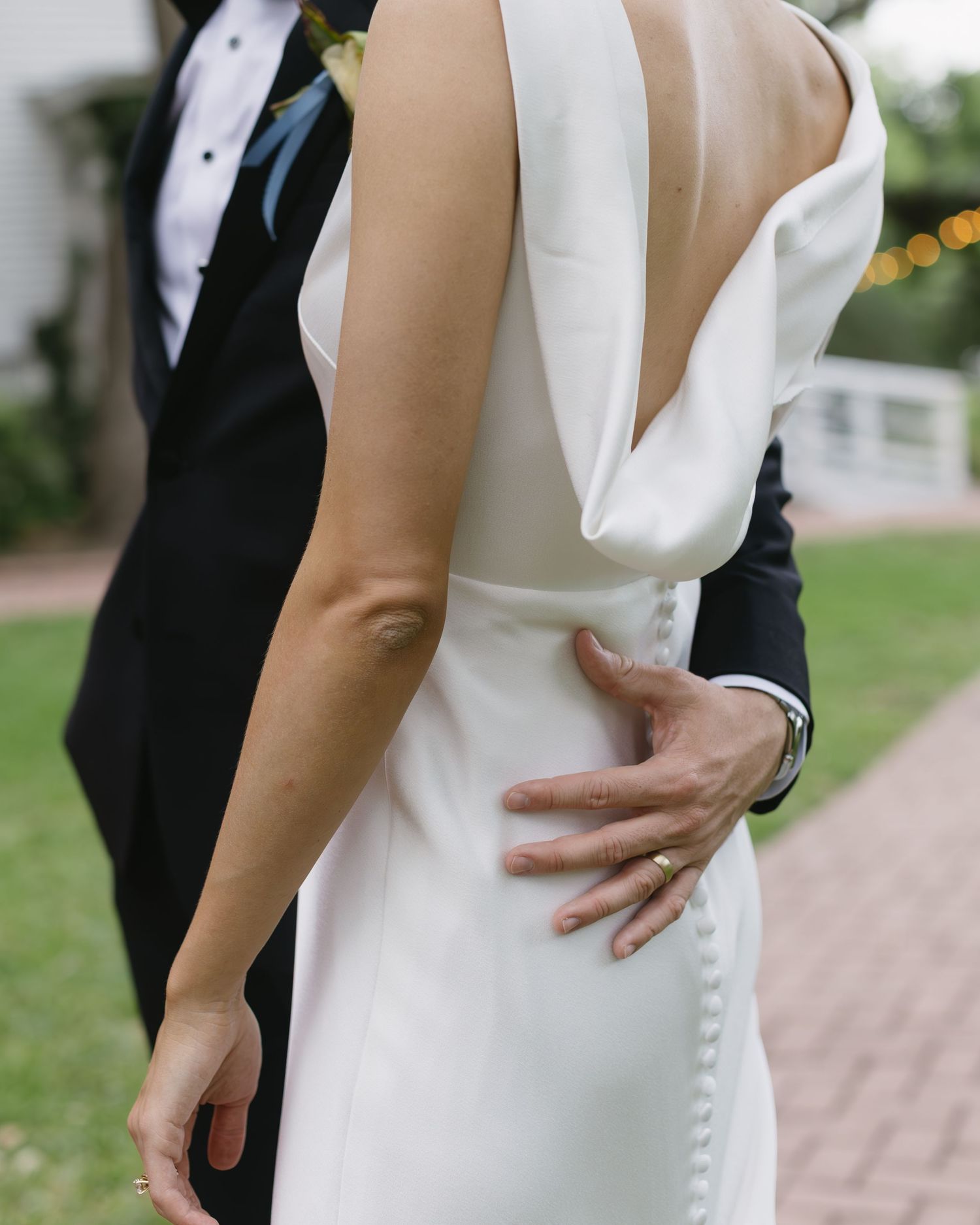 Close-up details of a white wedding dress and black tuxedo during intimate outdoor moments.