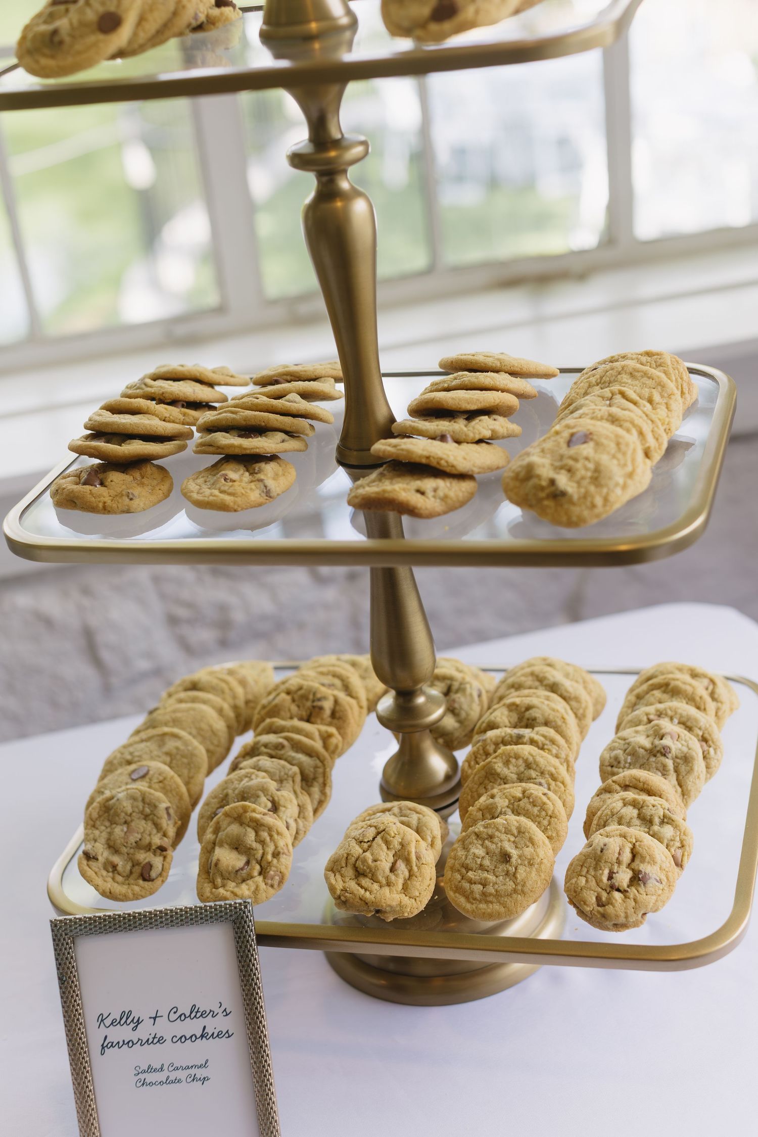 Golden tiered serving tray displaying homemade chocolate chip cookies at a wedding reception.
