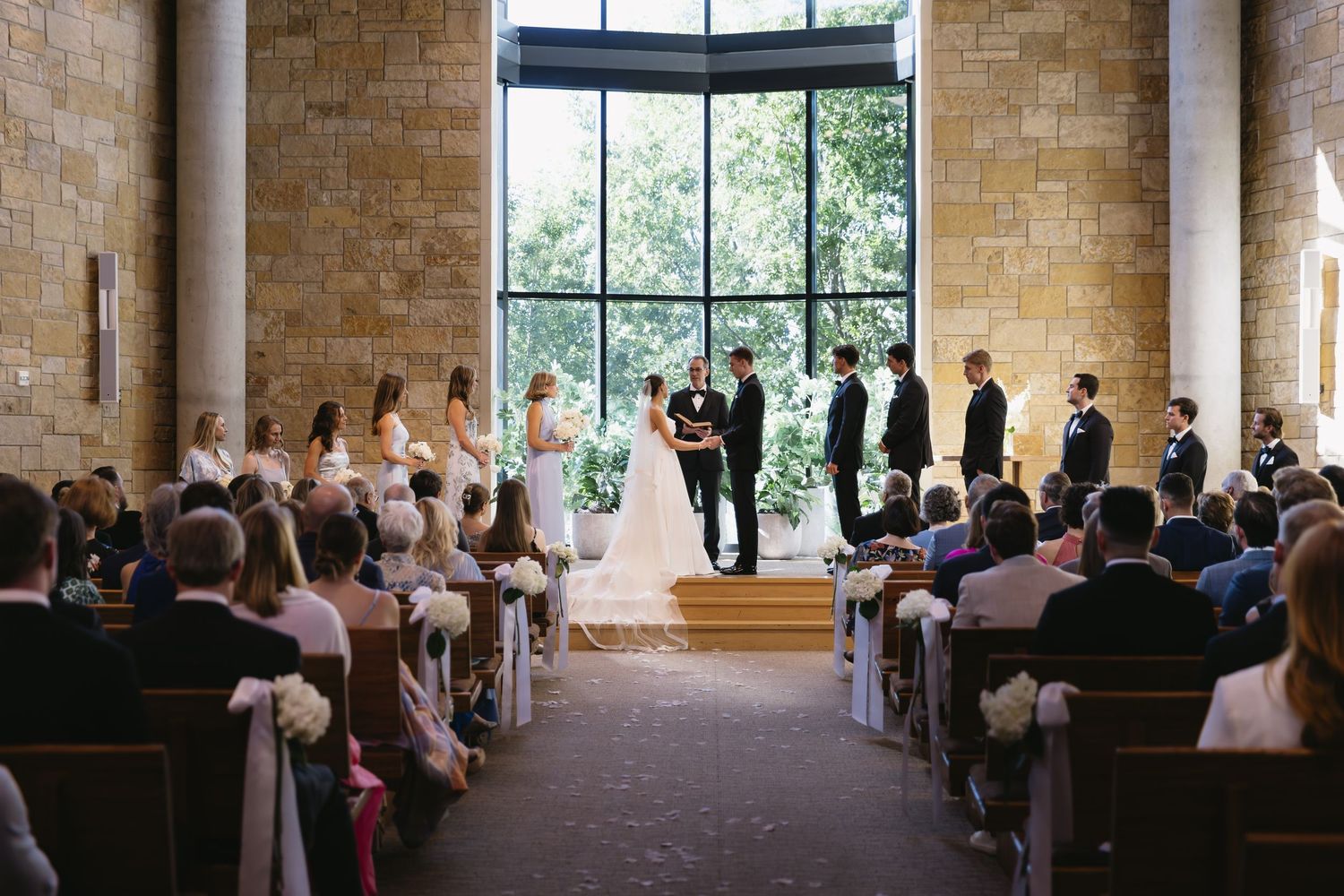 Church wedding ceremony in a beautiful brick chapel with large windows and natural light.