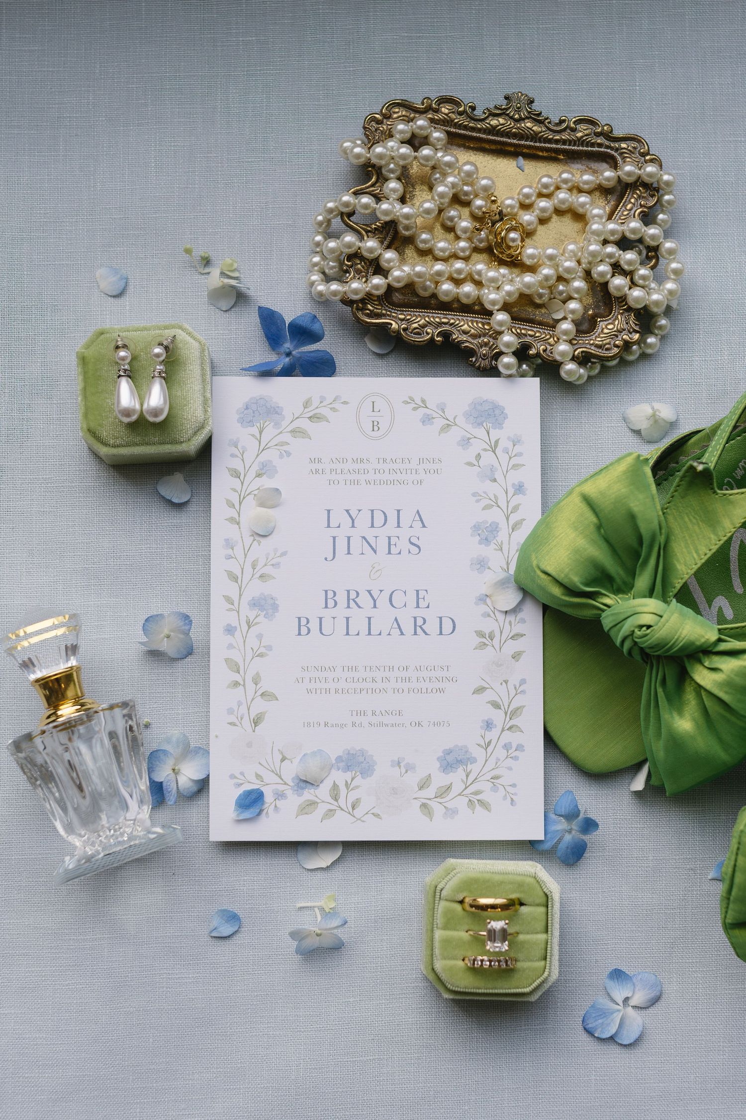Elegant wedding place cards with floral designs surrounded by blue petals and green foliage on a gray background.