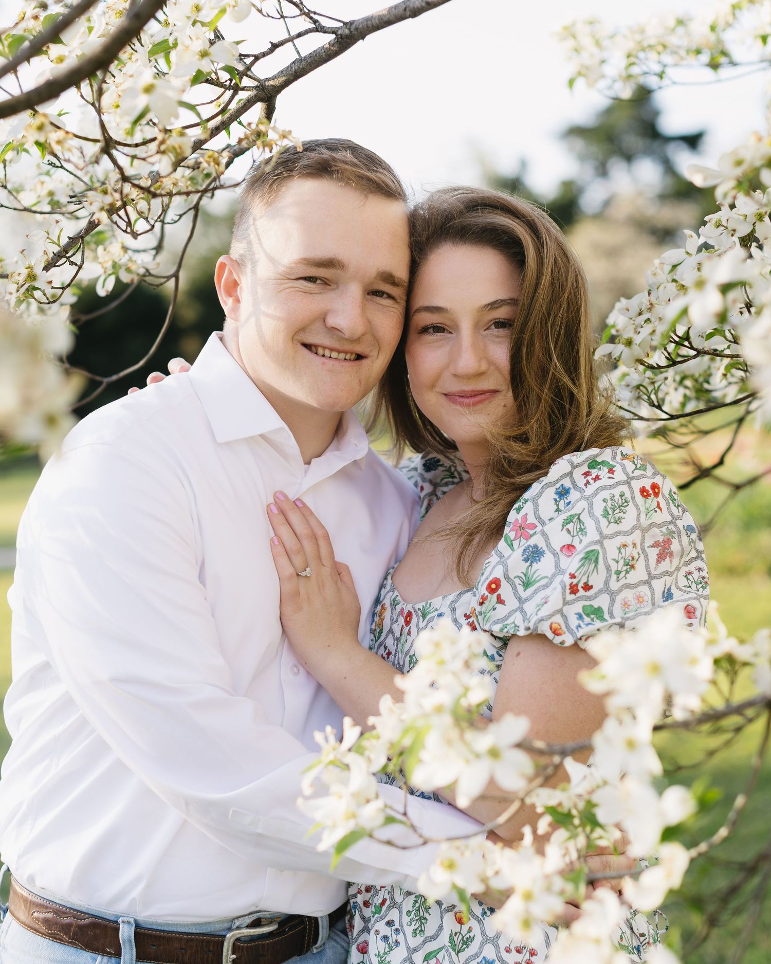 A couple shares an intimate moment among blooming spring cherry blossoms.