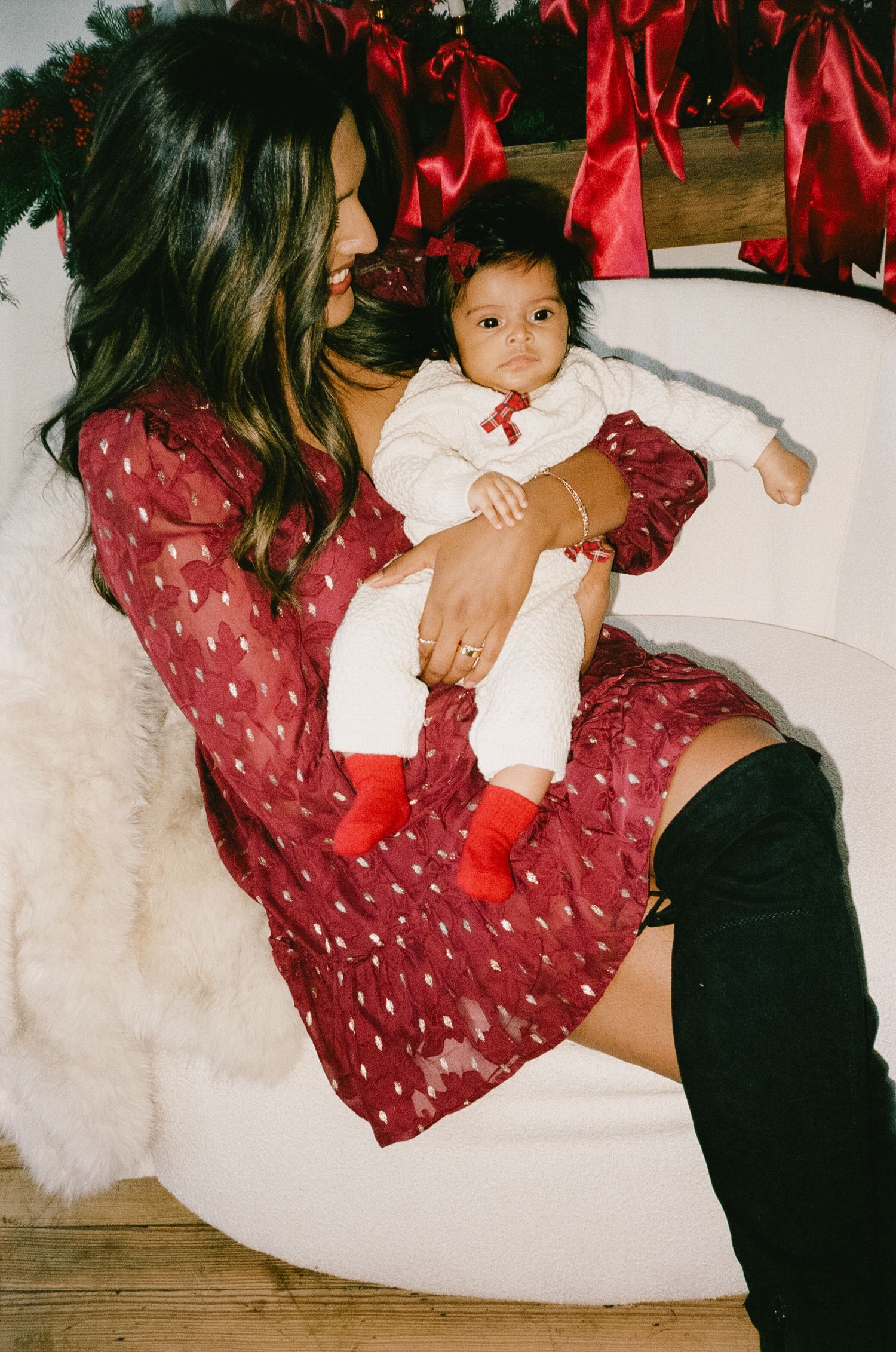 Intimate family moment captured during a holiday photoshoot with festive red decorations.