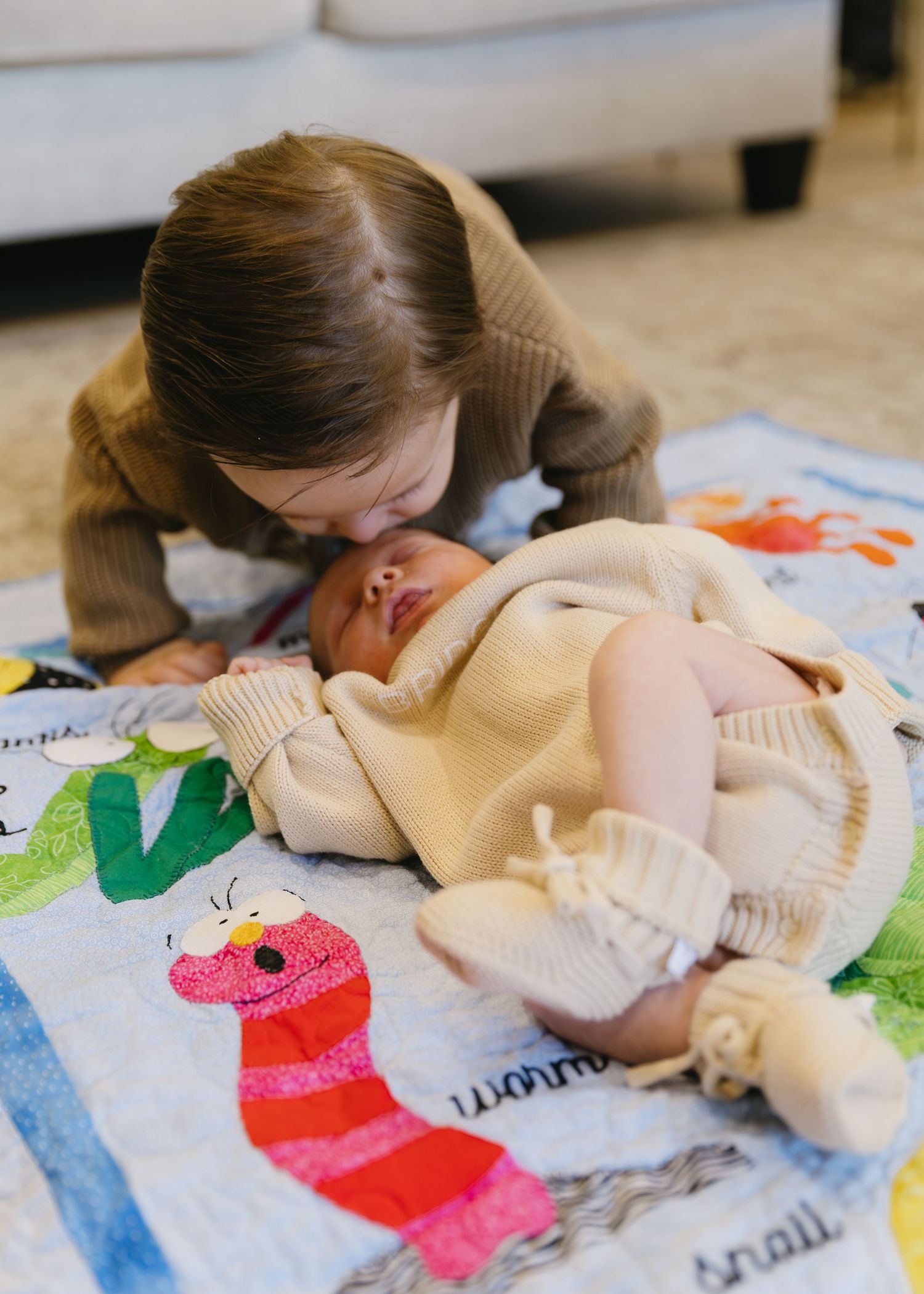 A sequence of images showing someone kissing a baby doll on a colorful play mat.