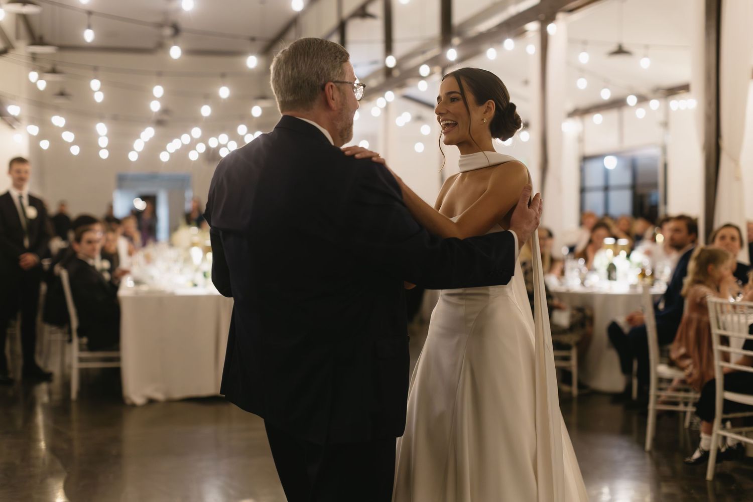 Wedding reception venue with string lights and guests enjoying the celebration.