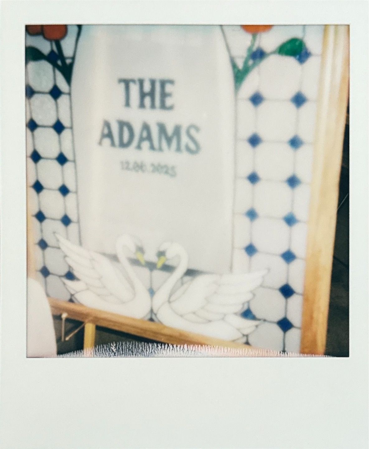 A polaroid-style photo showing a sign reading 'The Adams' against a patterned tile background.