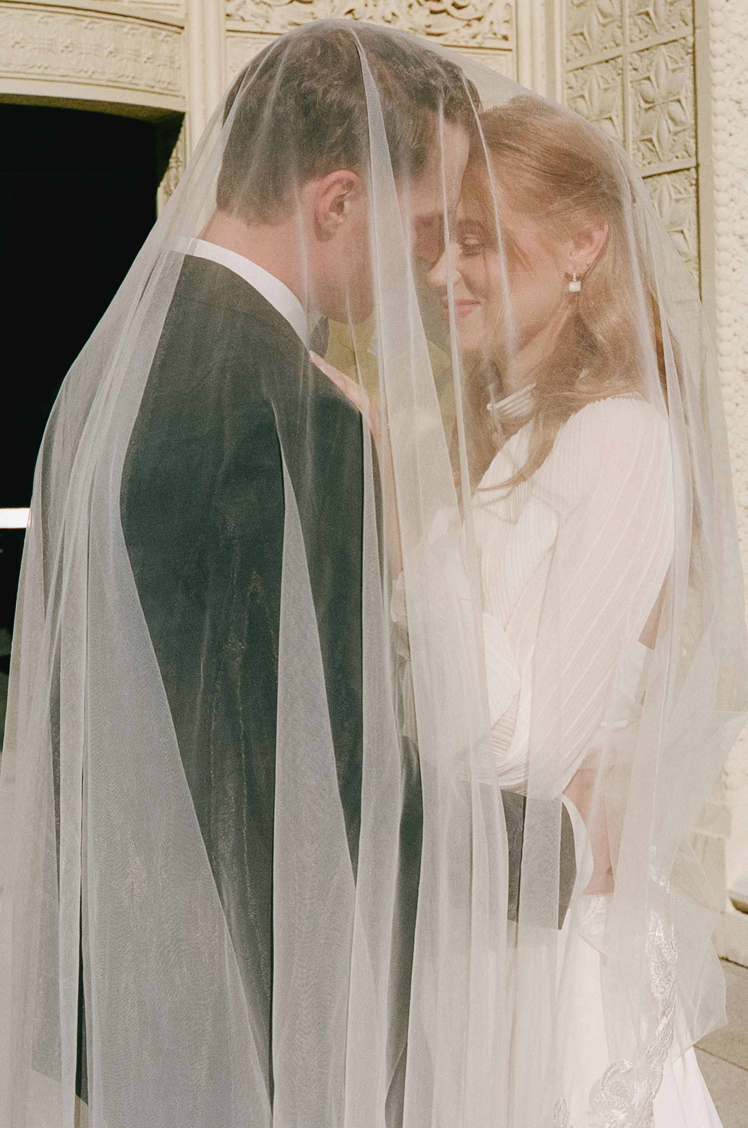 Romantic wedding portrait sequence through delicate white veil against ornate backdrop.