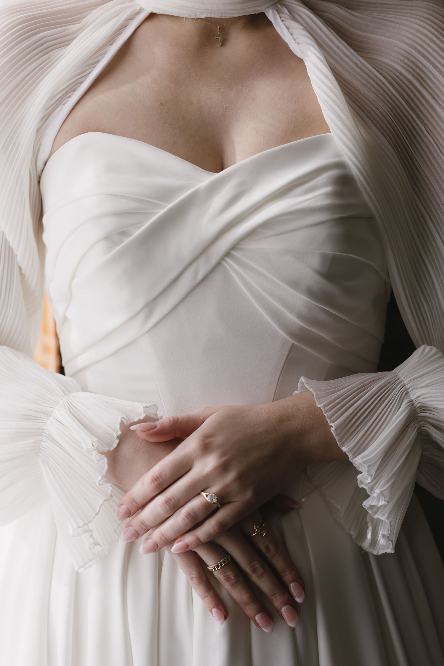 Close-up details of a pleated white wedding dress bodice with delicate fabric texture.
