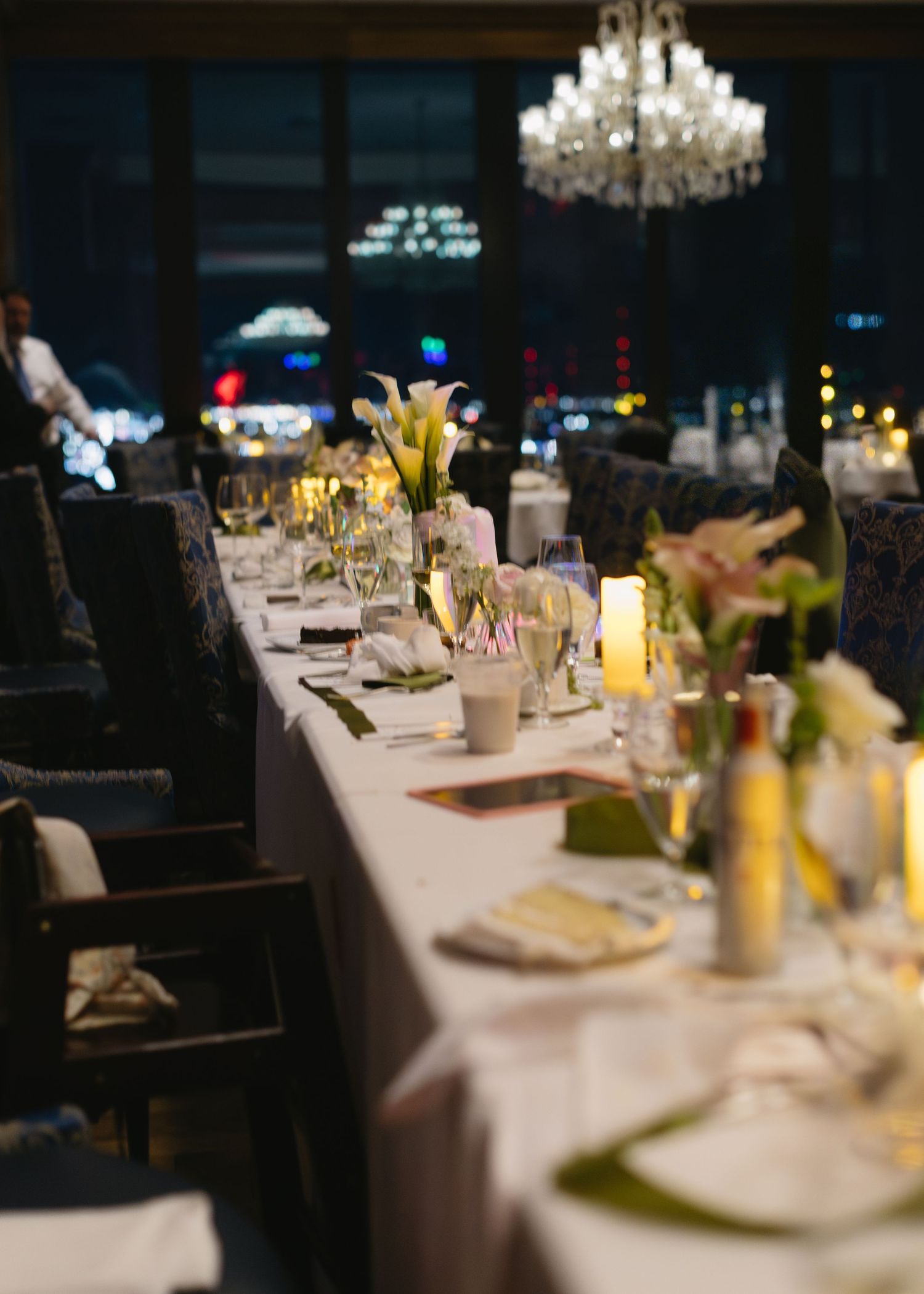 Elegant wedding reception table setting with white linens, floral centerpieces and crystal chandeliers.