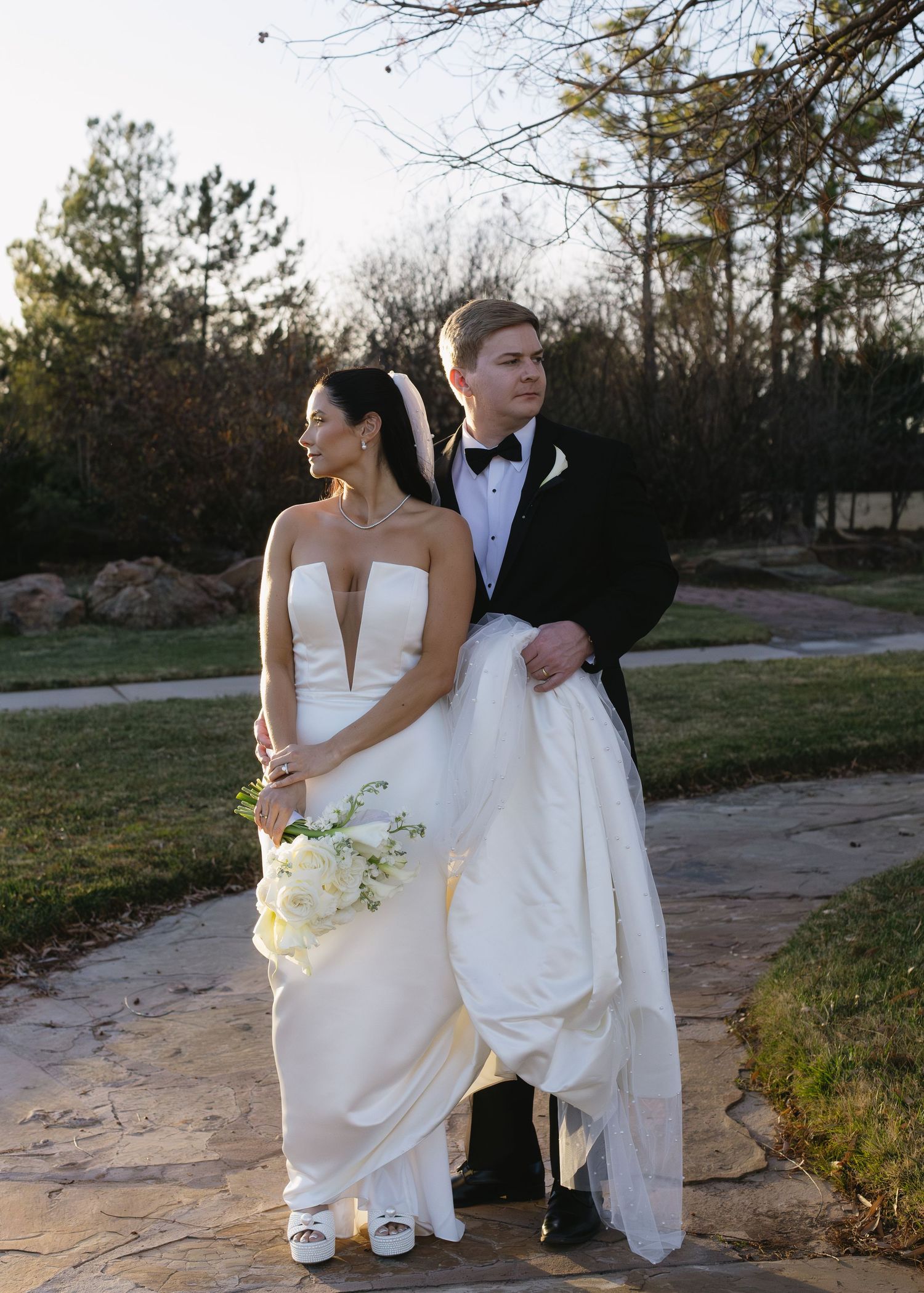Wedding couple poses together on stone pathway during outdoor photo session.