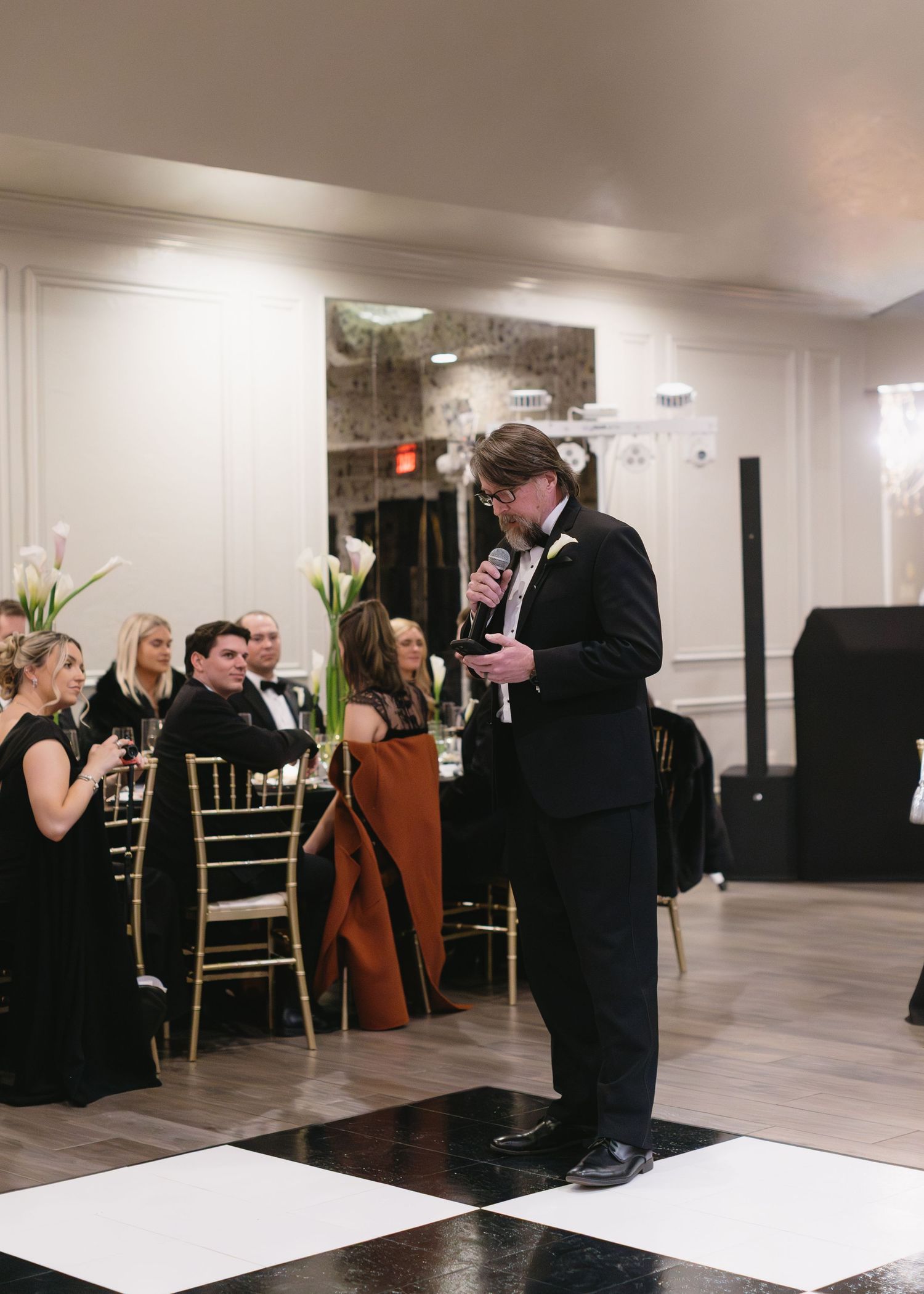 Wedding guests dance and mingle at an elegant reception with gold chairs and white decor.