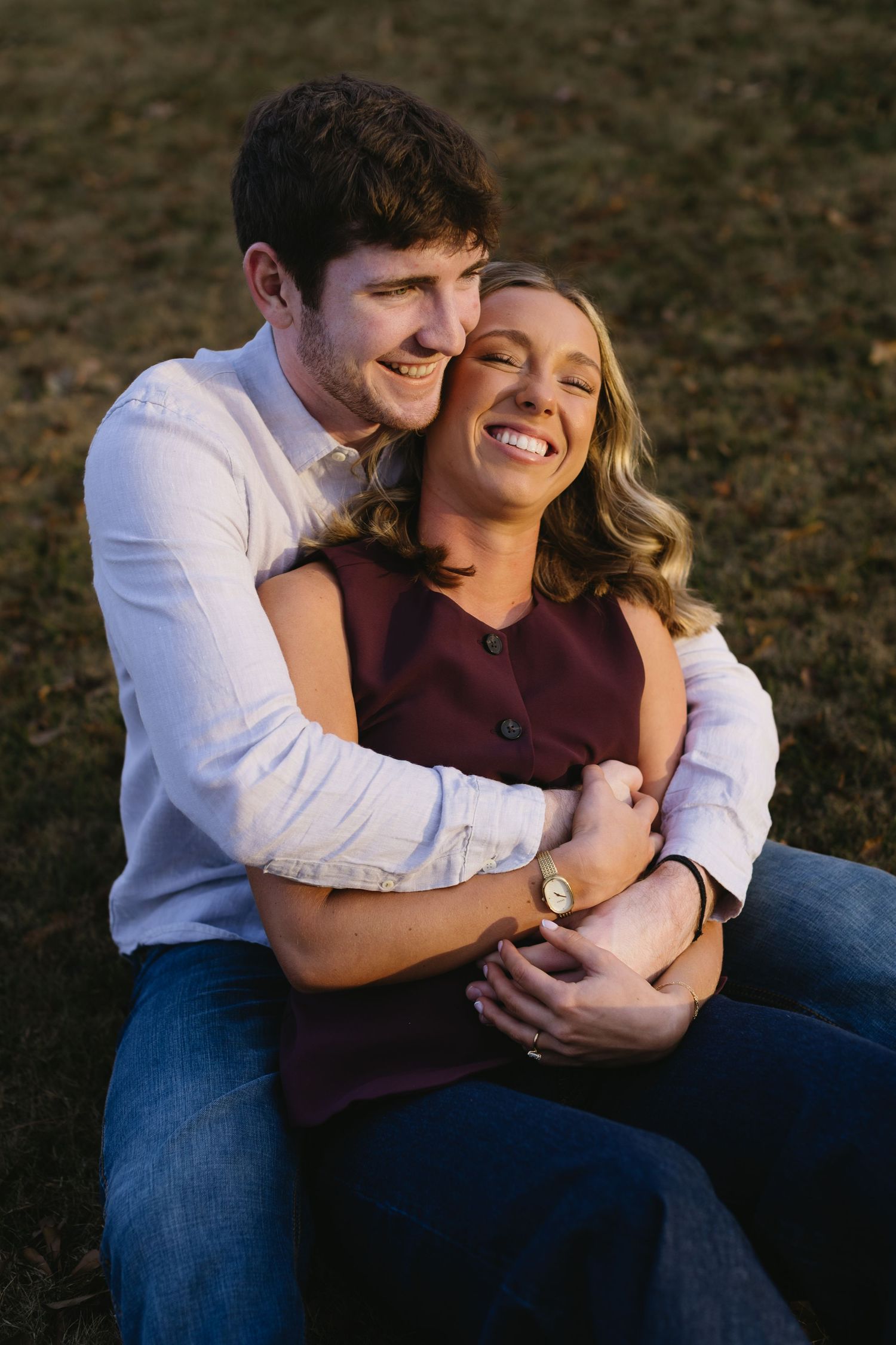 An intimate moment between a couple laughing together outdoors at sunset.