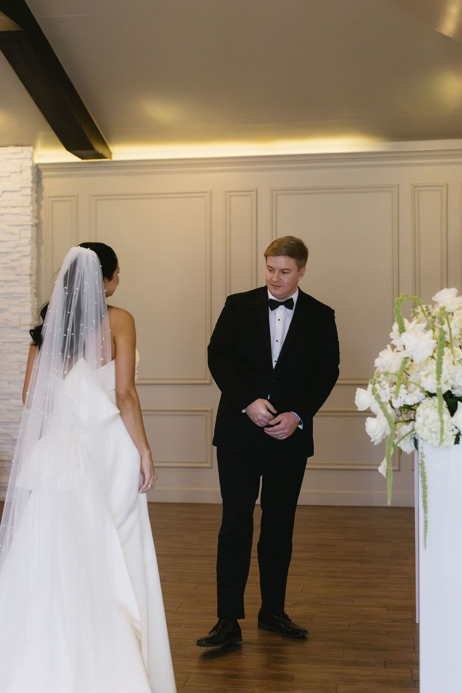 Wedding dress and tuxedo in an elegant room with white paneled walls.