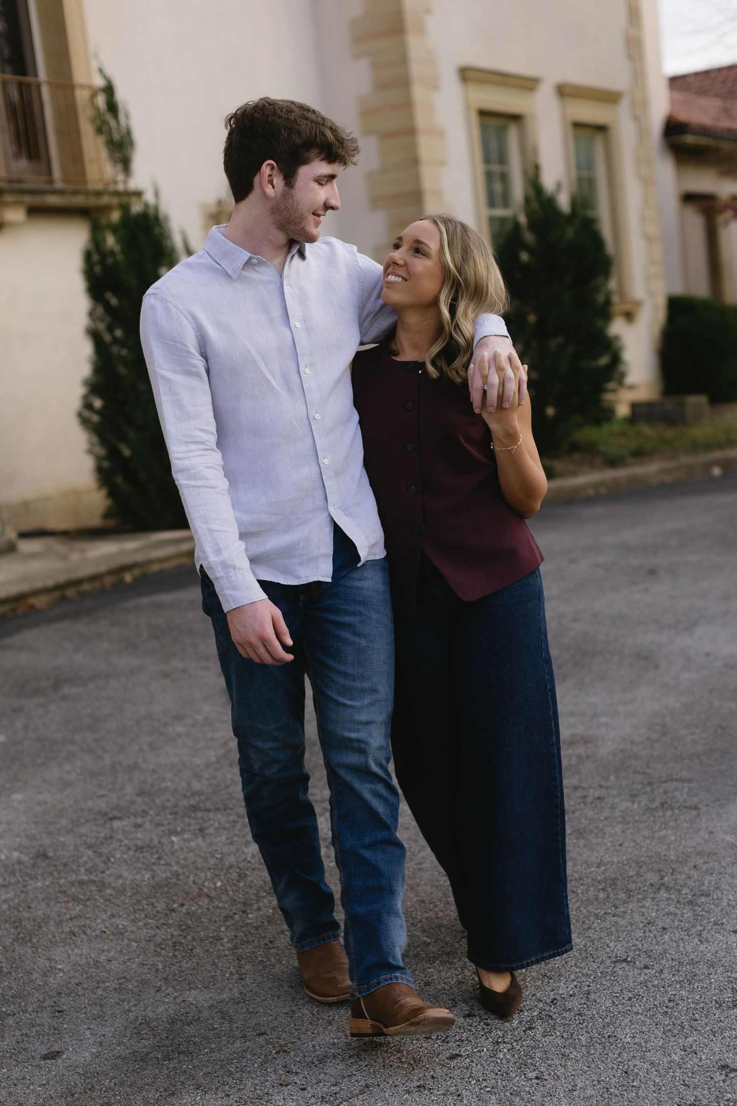 A couple walking and laughing together on a street, dressed in casual autumn attire.
