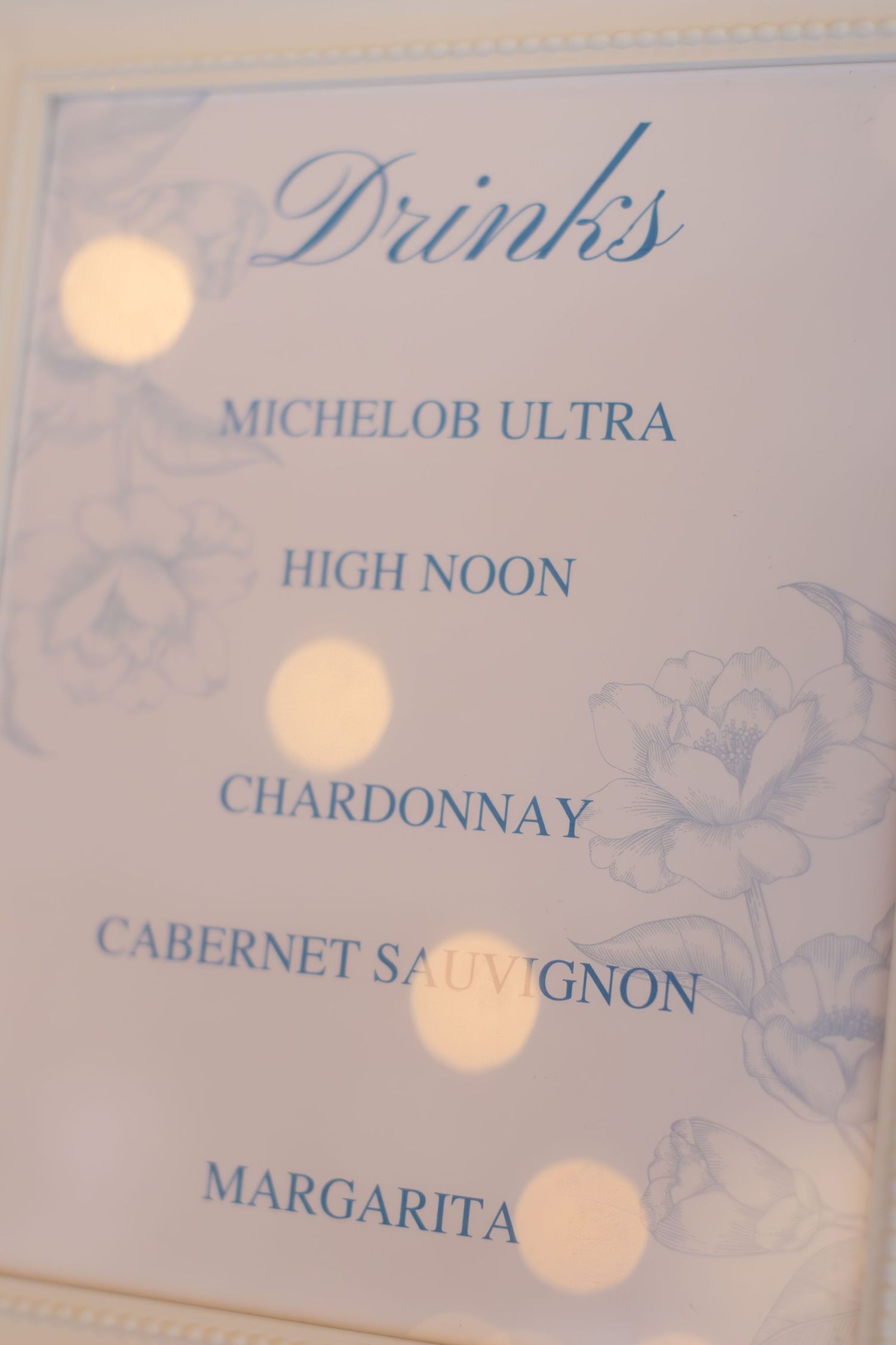 A wedding drinks menu features wine and cocktail selections in elegant blue lettering.