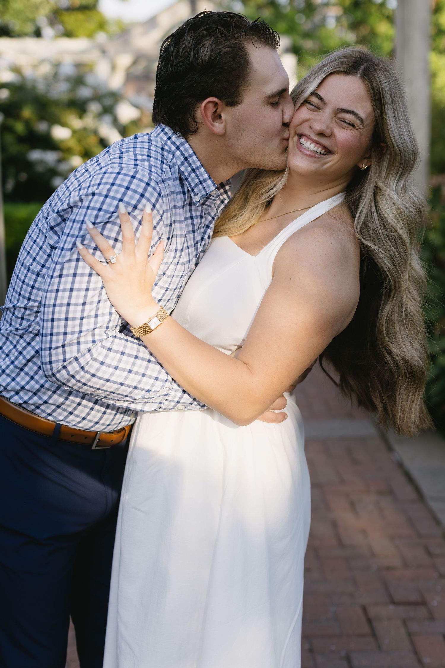 Intimate moment captured between couple in white and navy outfits during sunny outdoor photoshoot.