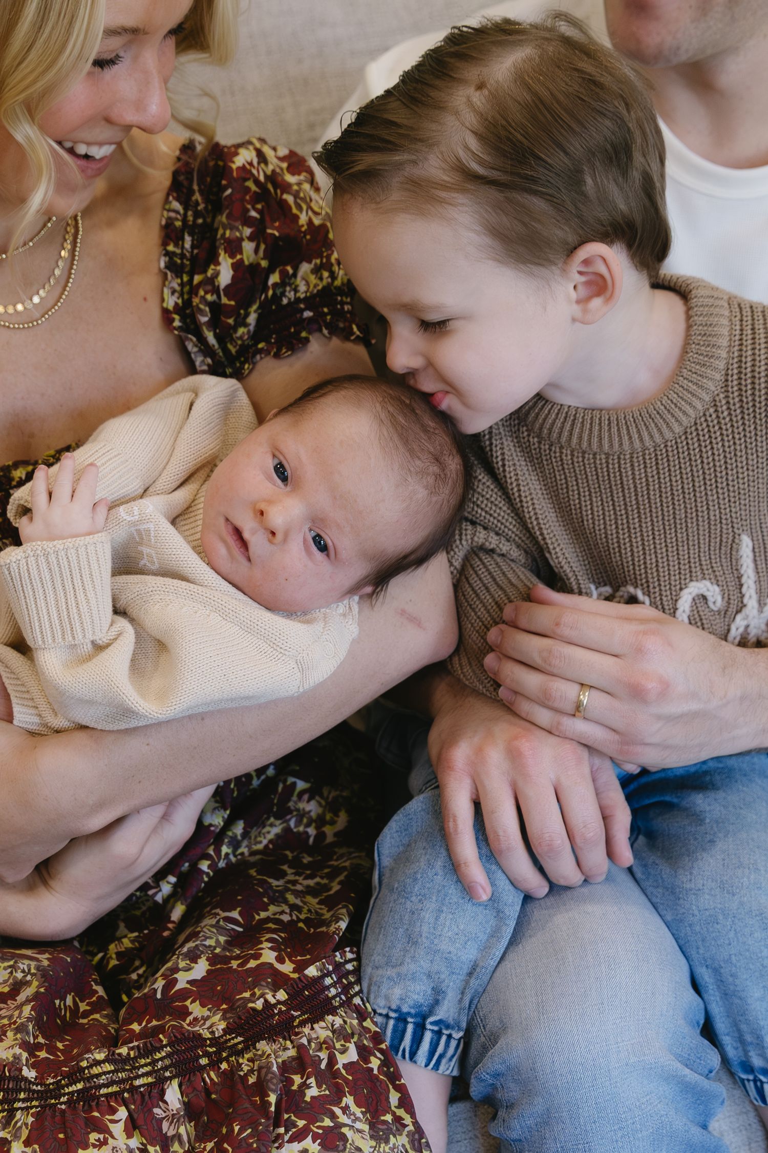 A series of candid family moments showing tender embraces between parent and child on a floral patterned couch.