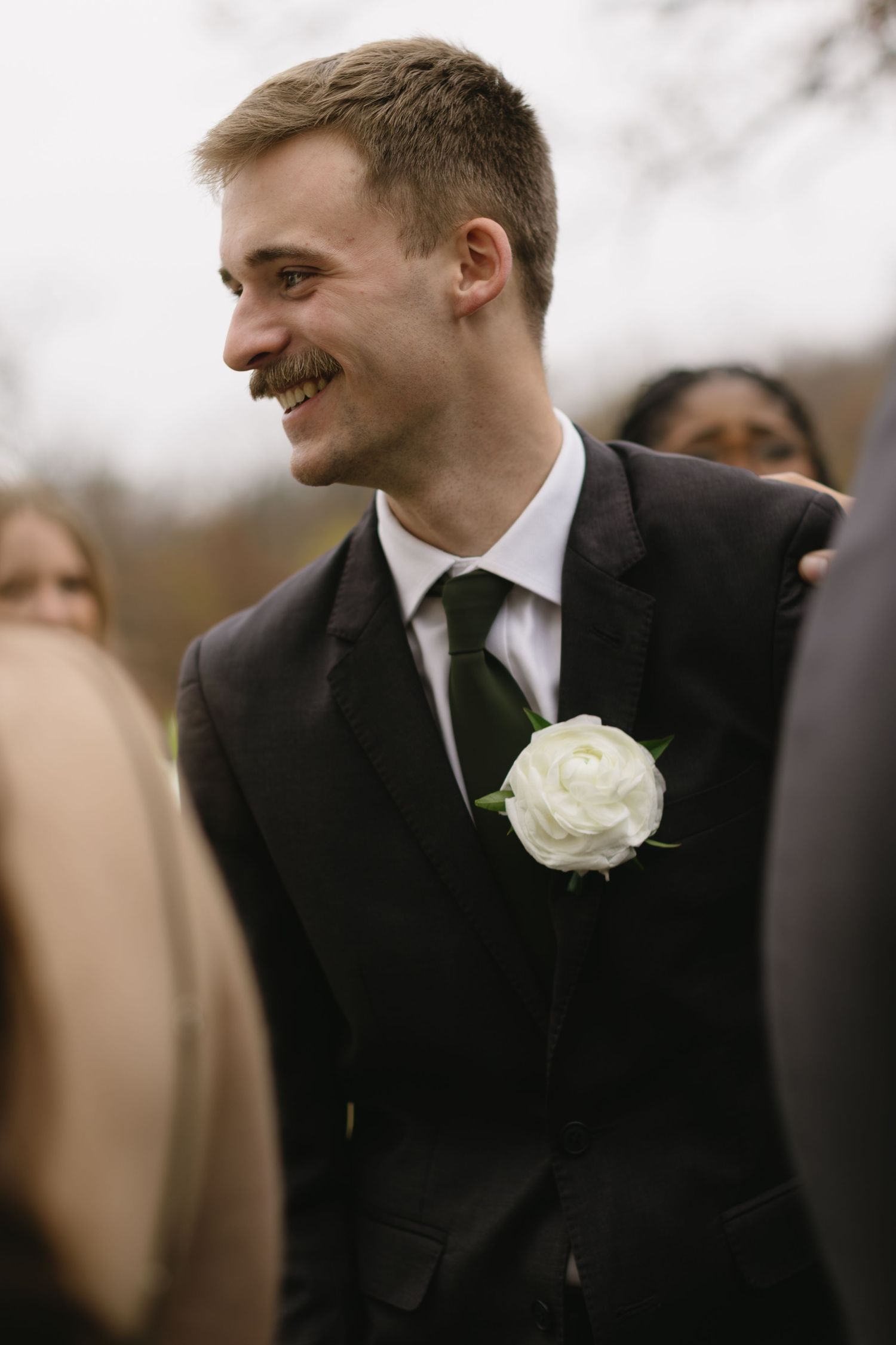 Groomsmen in black suits with white boutonnieres smile during wedding celebration.