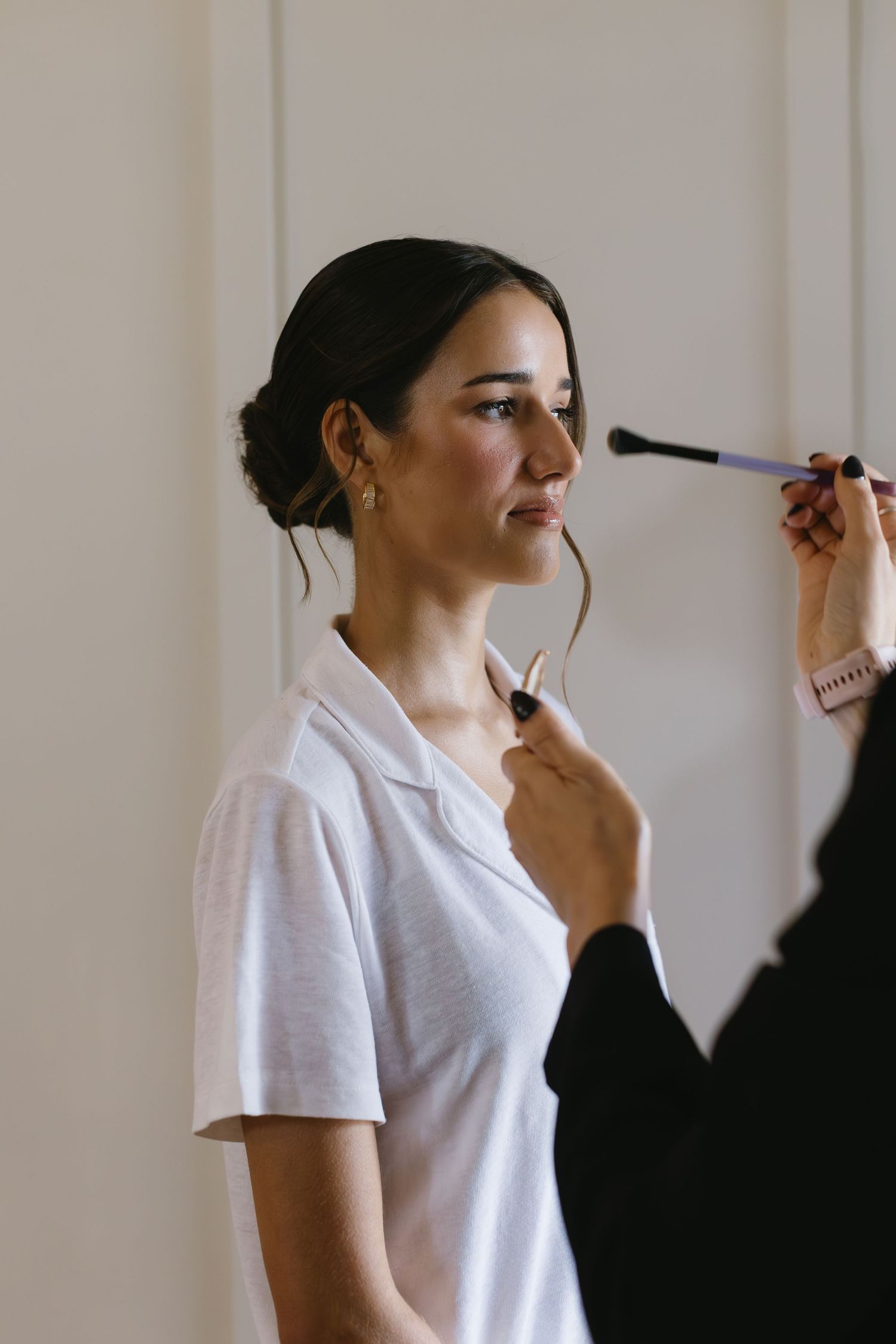 A series of getting ready photos showing makeup application in a white t-shirt against a light background.