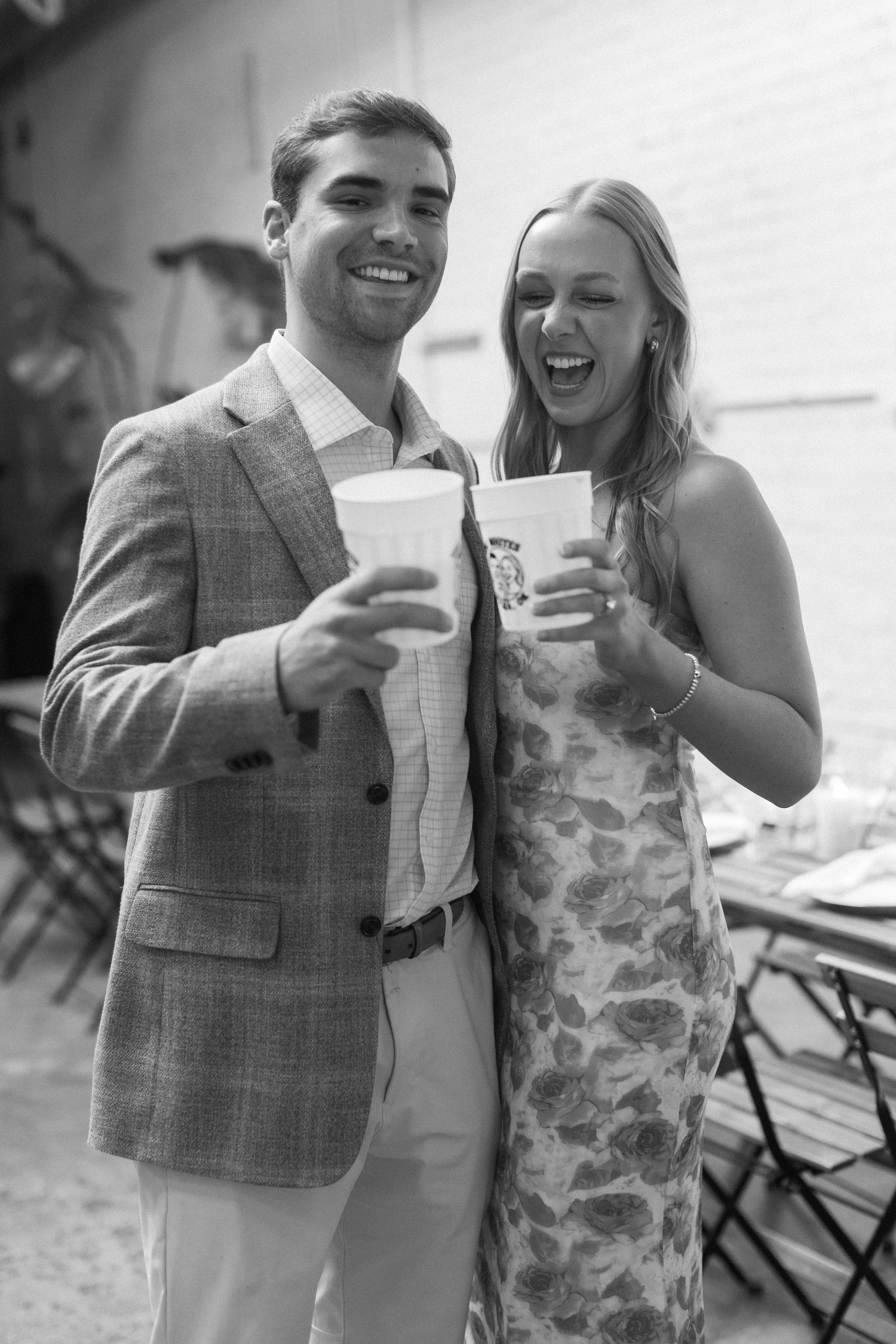 Black and white candid photos of couple laughing and holding drinks at outdoor event.