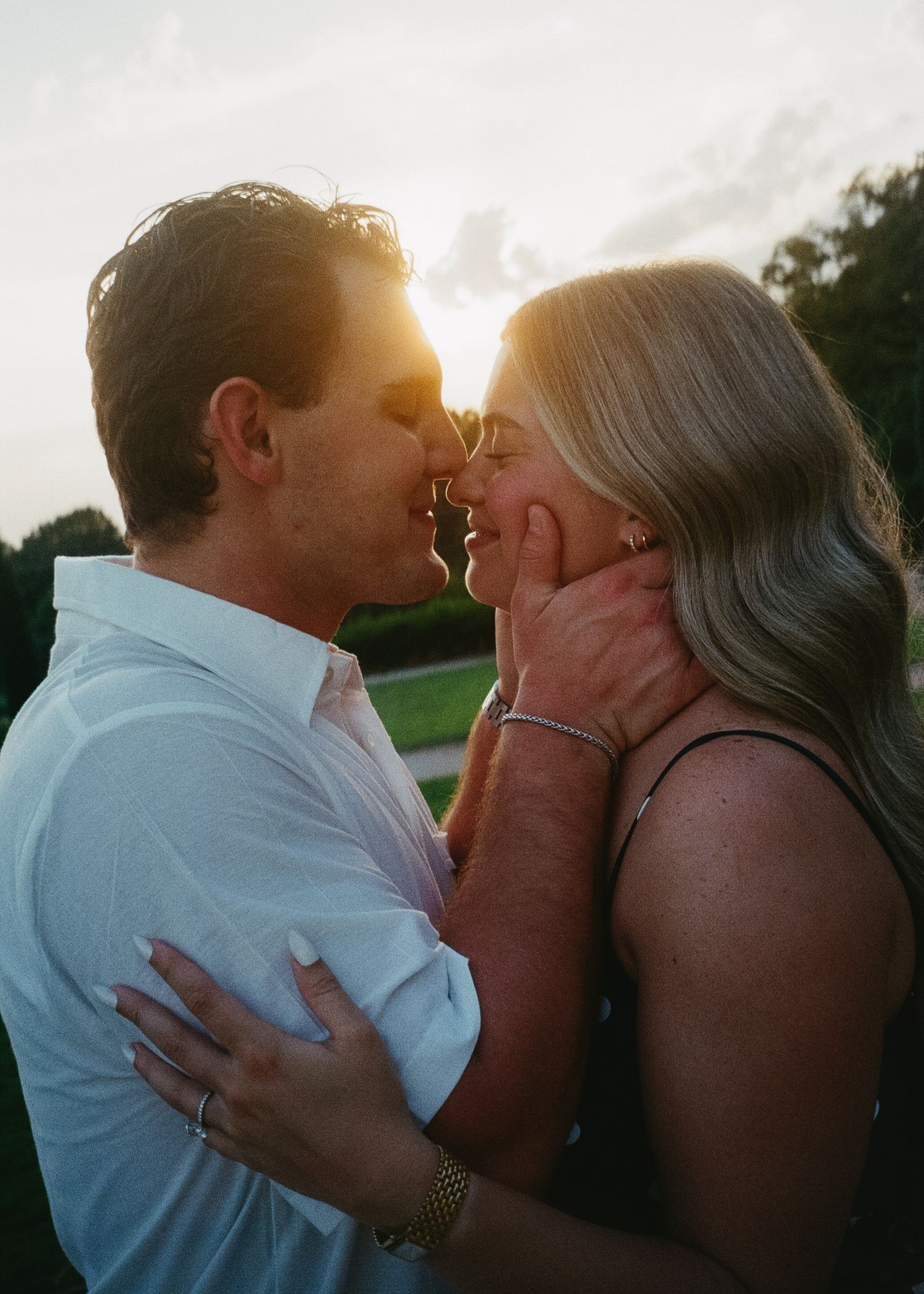 A romantic sunset silhouette of a couple embracing and kissing in golden evening light.