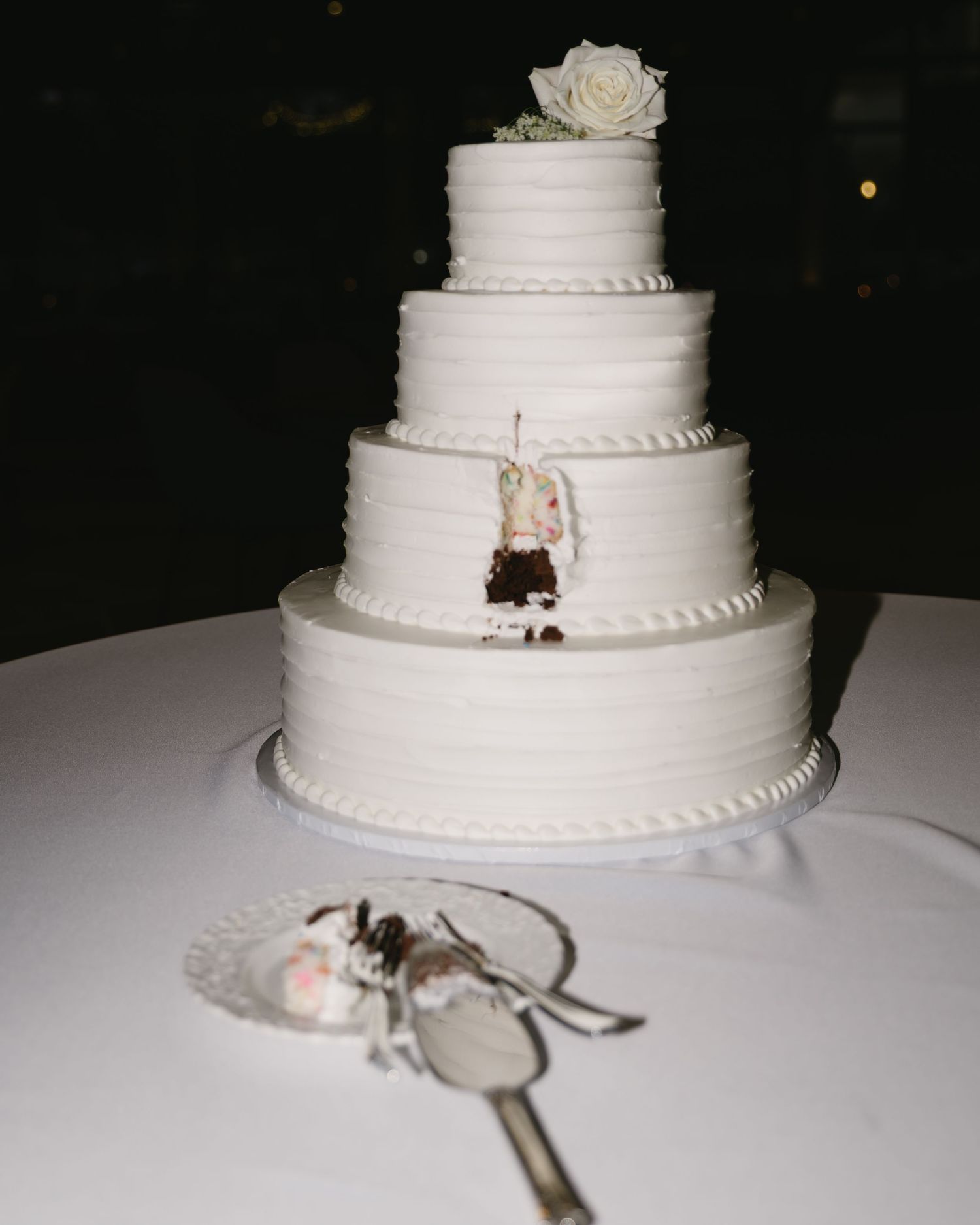 A series of shots showing a classic white tiered wedding cake with delicate decorative details on a table.