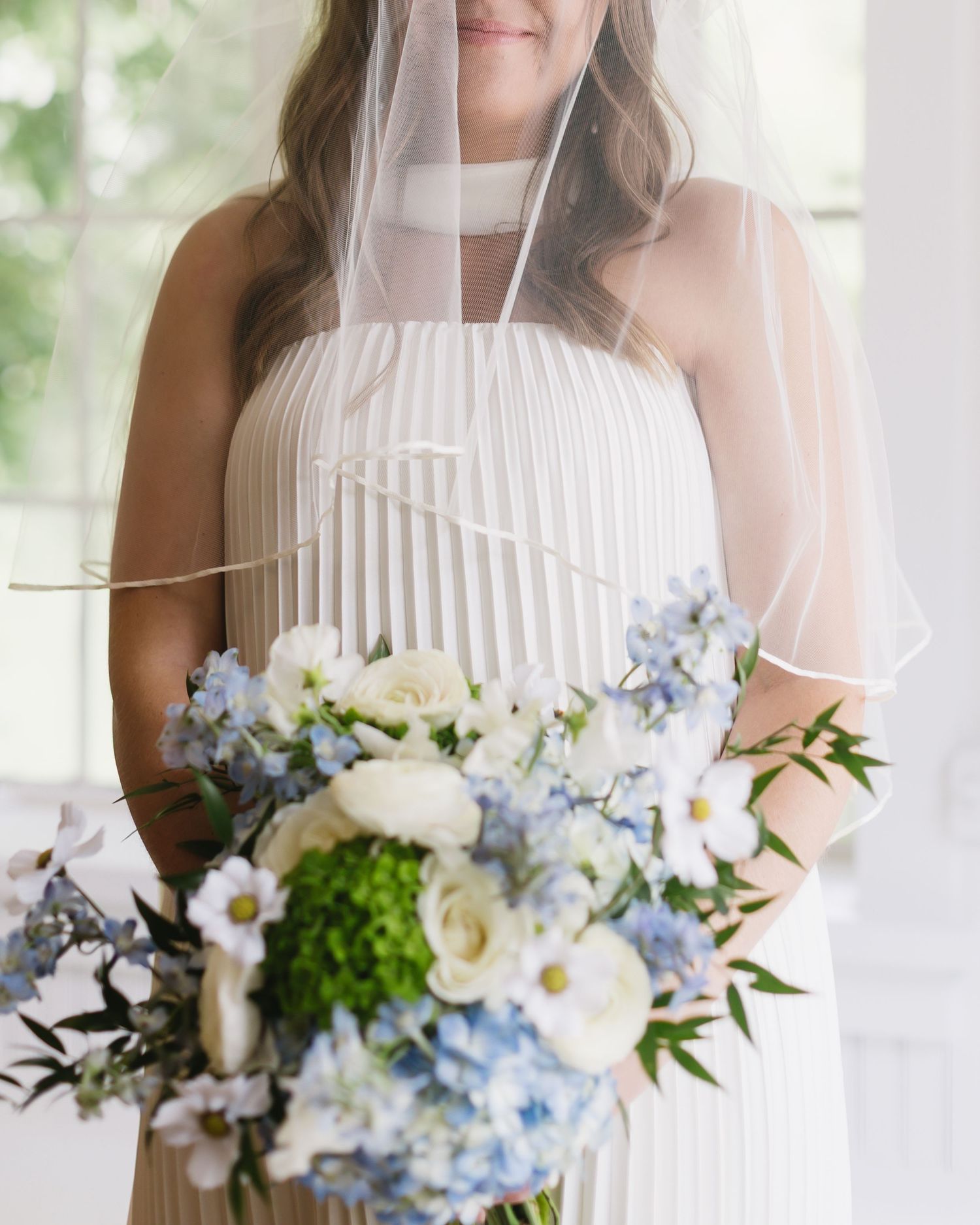 Wedding bouquet featuring white and light blue flowers with greenery accents.