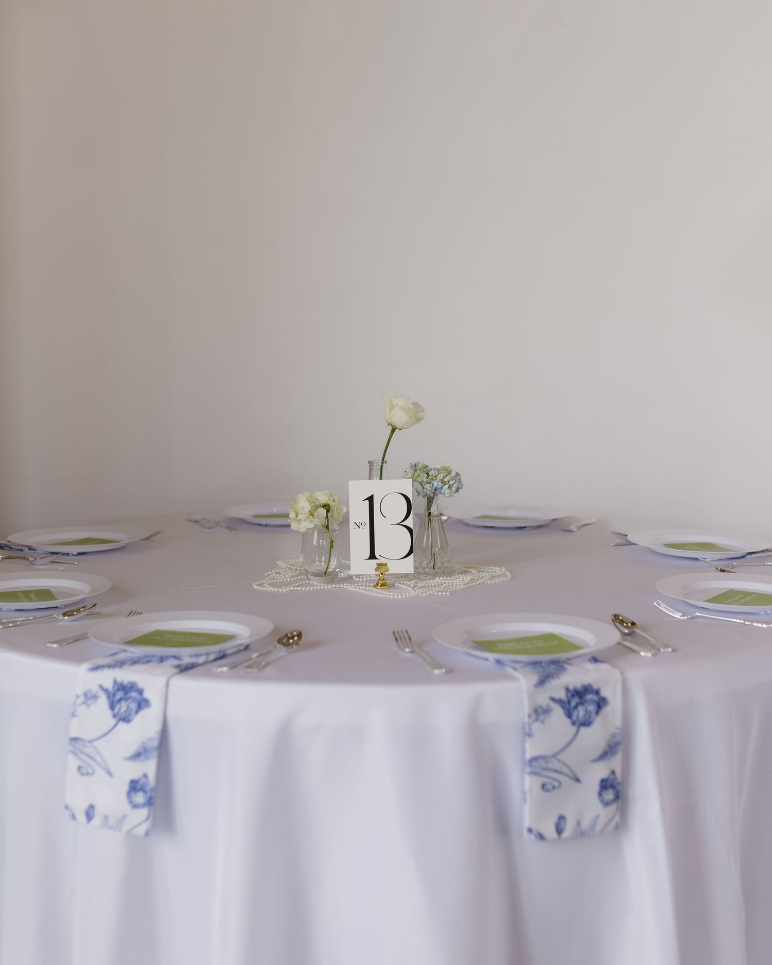 White tablecloths with blue and white table settings at a formal event.