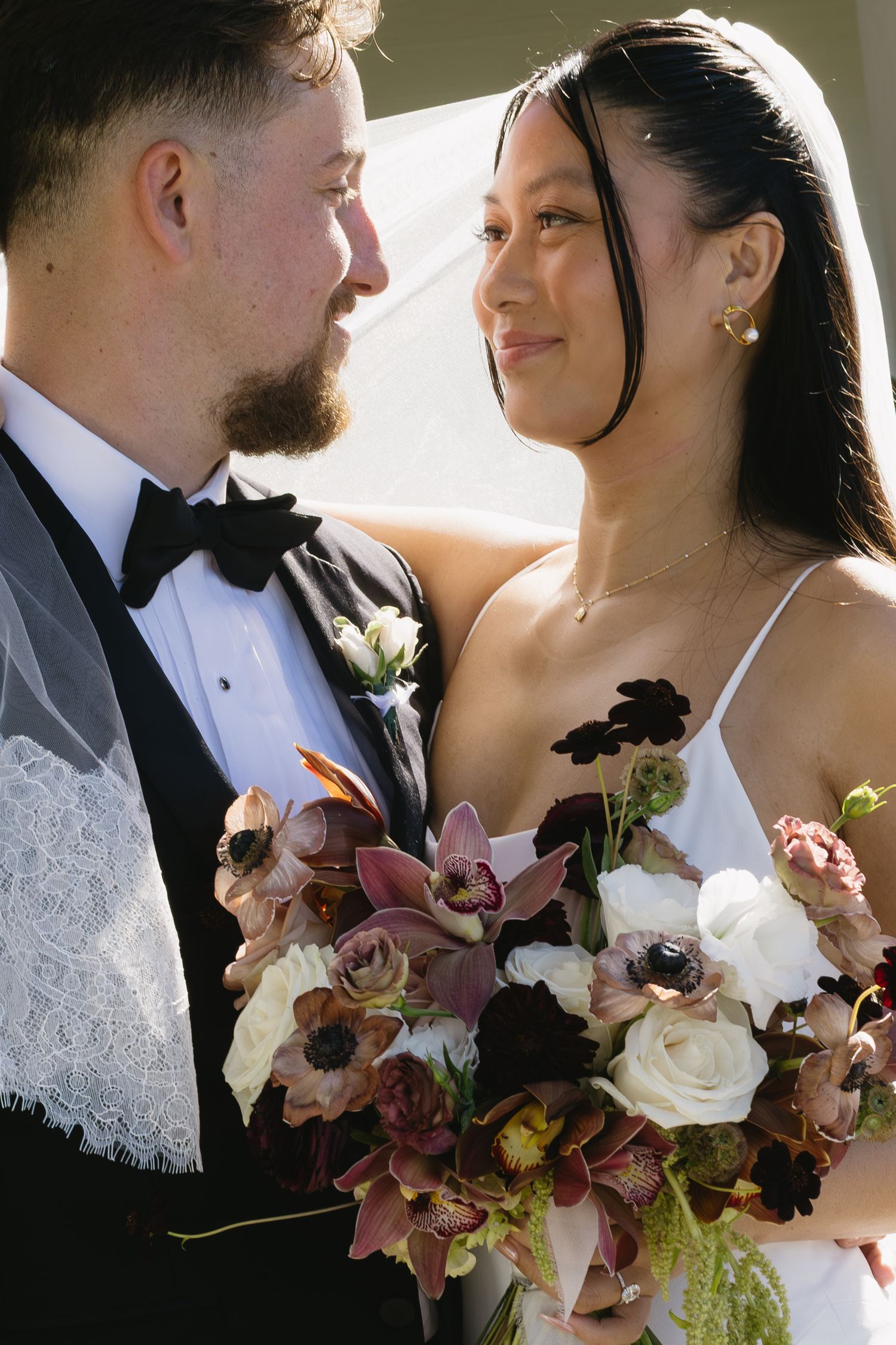 Romantic wedding portrait with couple holding a bouquet of mauve and white flowers.